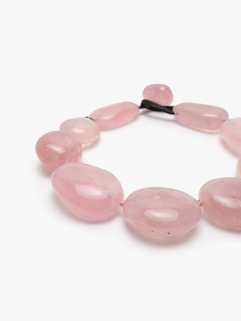 A necklace made of rose quartz with a leather clasp.