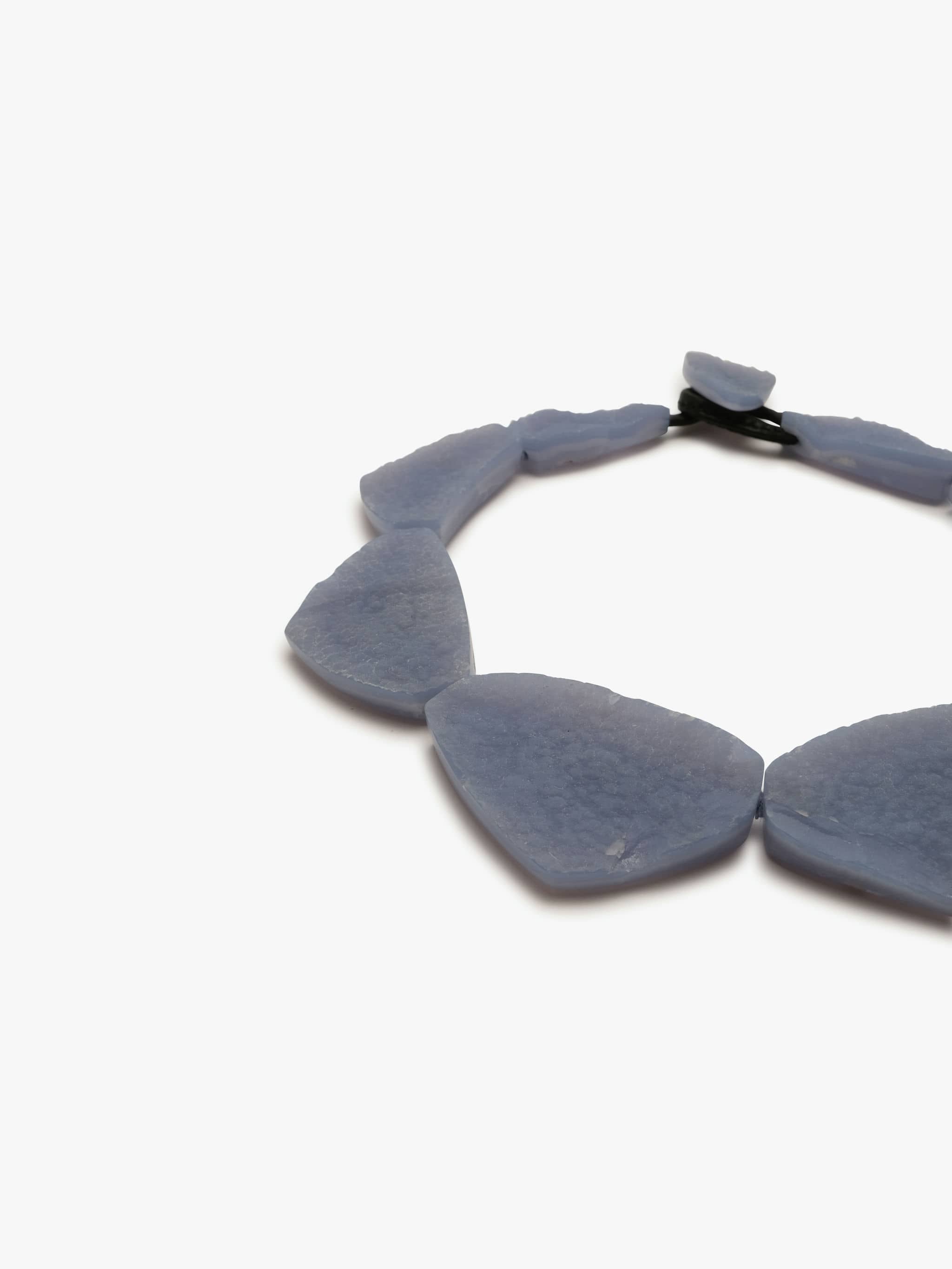 A blue chalcedony necklace with a toggle clasp lock and leather detailing.