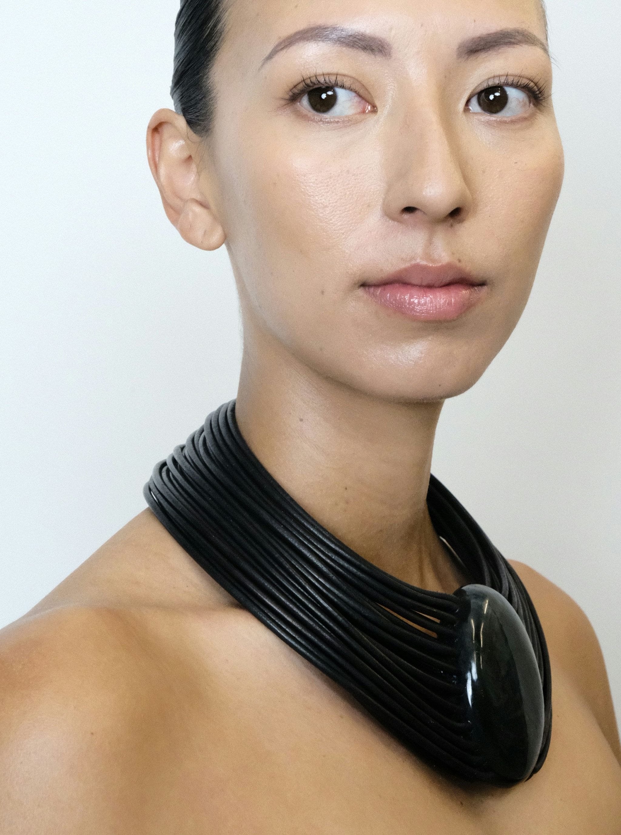 a woman wearing a black leather necklace with a central labradorite stone and a bog oak magnetic lock.