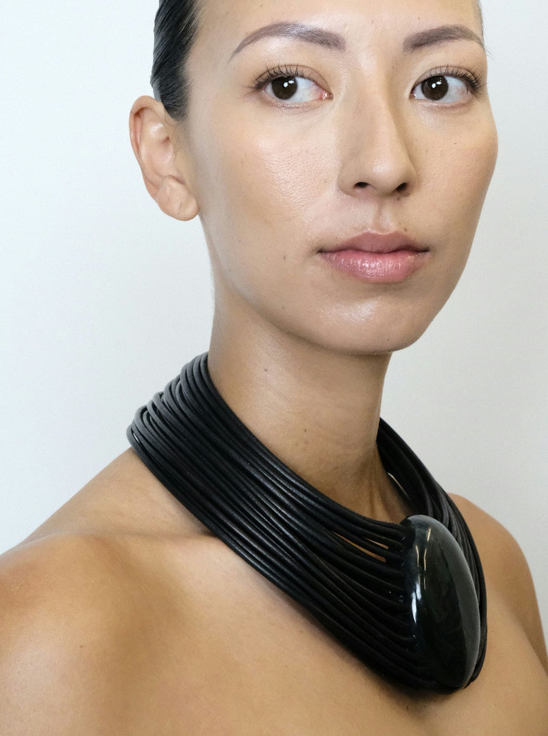 a woman wearing a black leather necklace with a central labradorite stone and a bog oak magnetic lock.