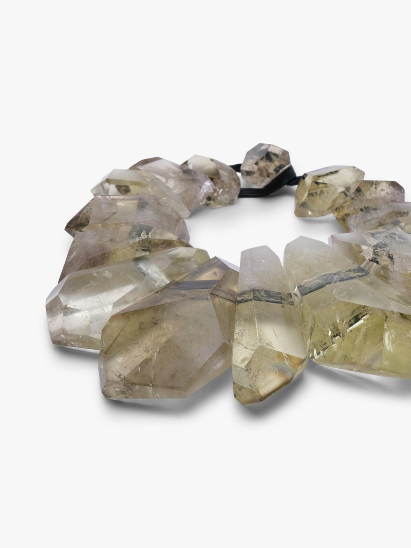  a beaded necklace featuring faceted, yellow citrine beads with natural inclusions, threaded on a black elastic band, set against a plain white background.