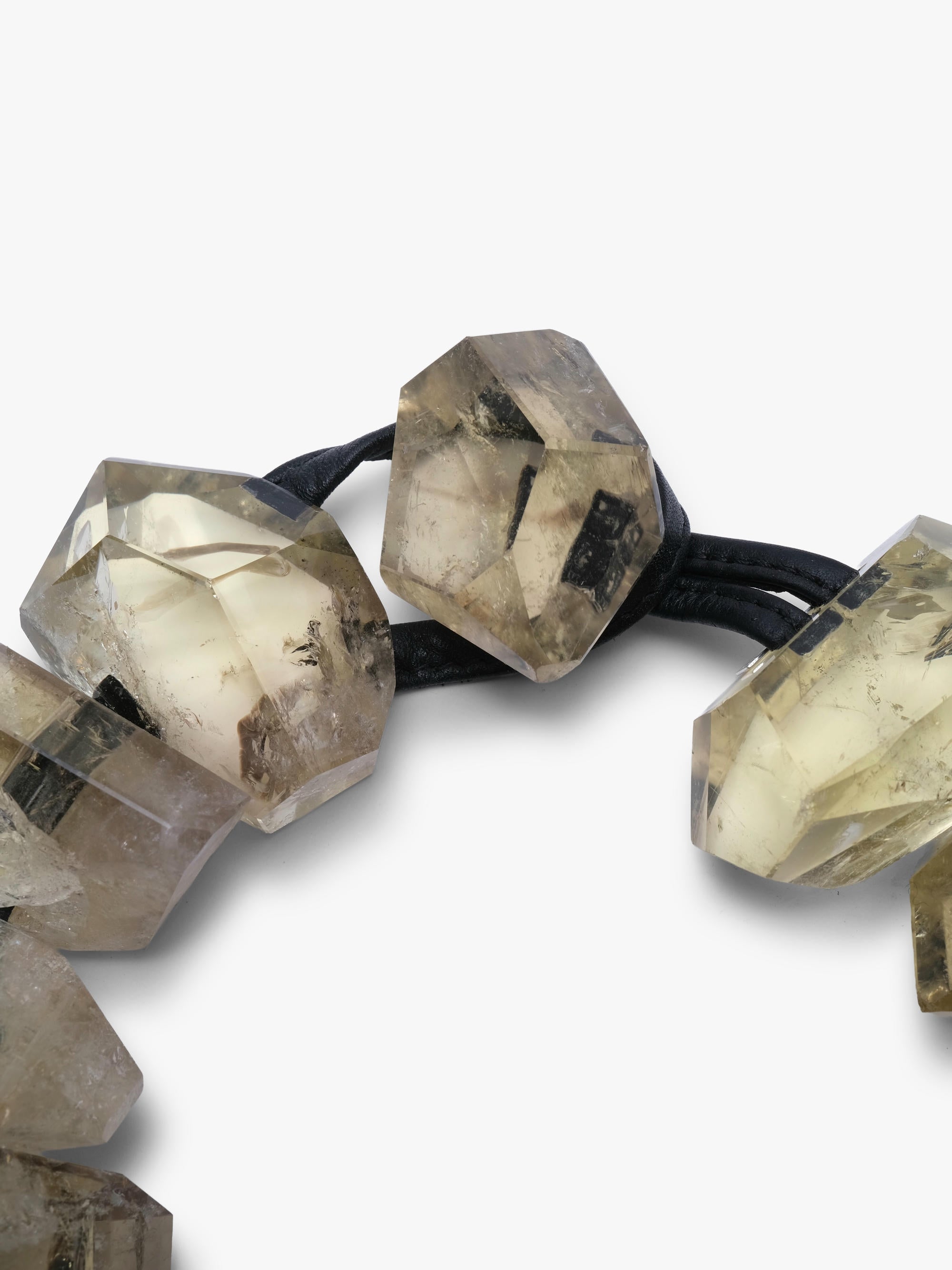 A close-up of a beaded necklace featuring faceted, yellow citrine beads with natural inclusions, threaded on a black elastic band, set against a plain white background.