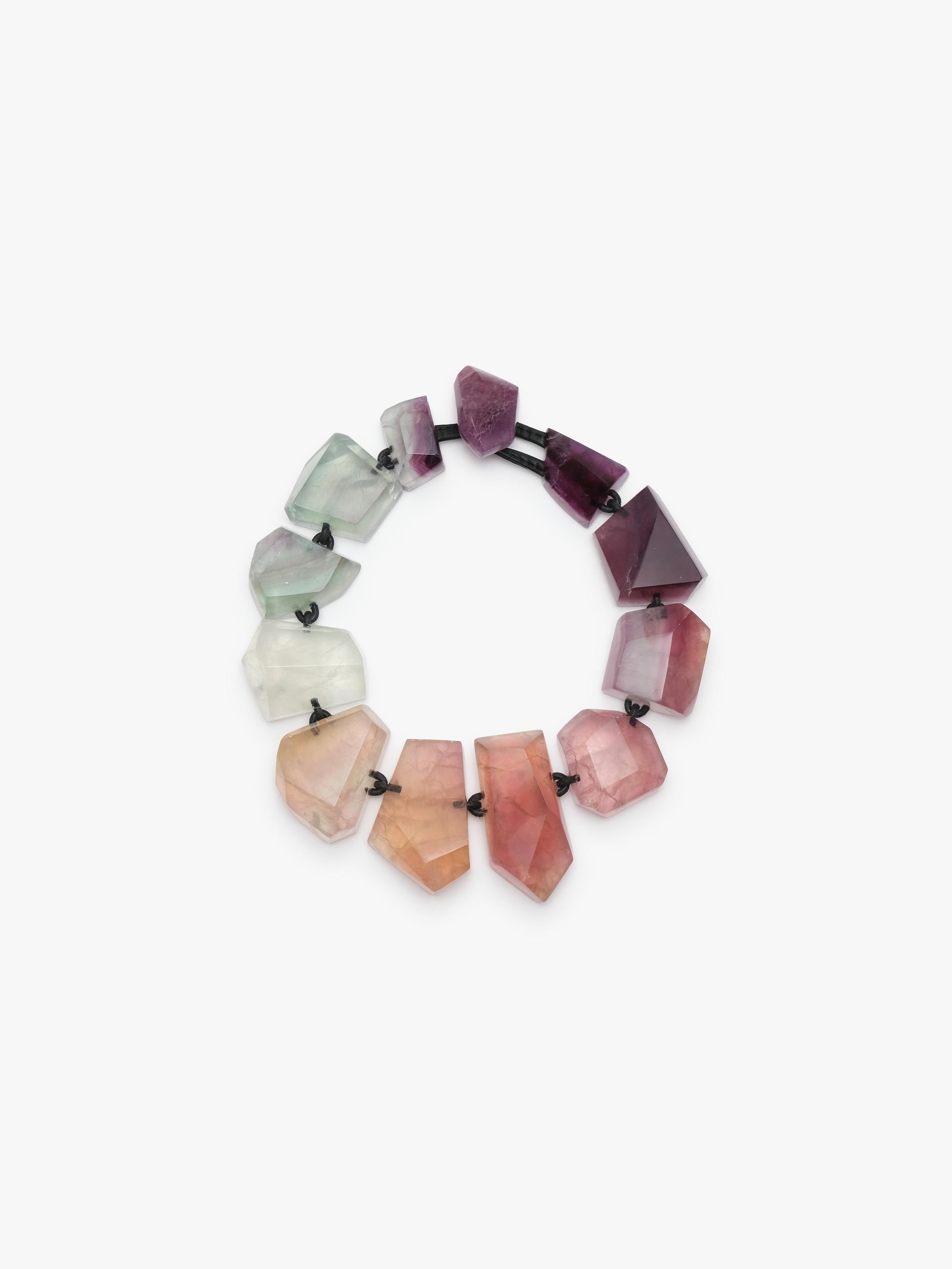 A necklace made of irregular, faceted gemstone beads in a gradient of colors from pale green and white to pink and deep purple, strung on a black elastic band, shown against a plain white background.