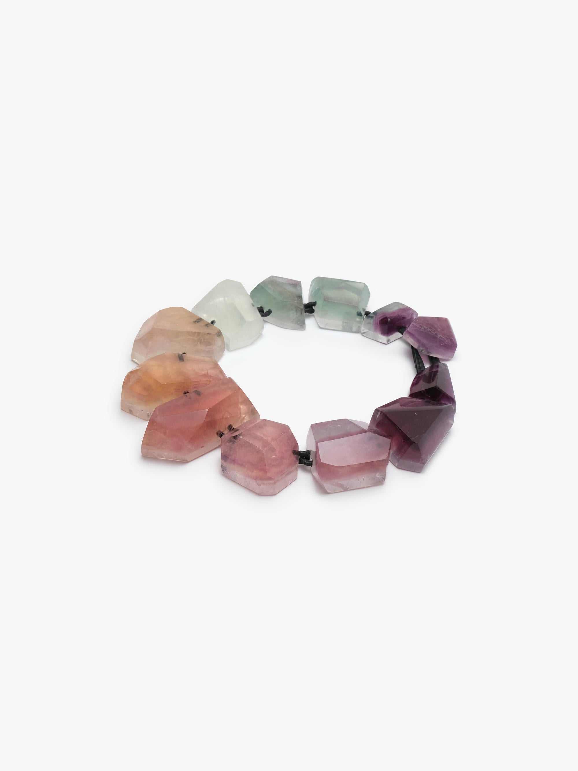 A necklace made of irregular, faceted gemstone beads in a gradient of colors from pale green and white to pink and deep purple, strung on a black elastic band, shown against a plain white background.
