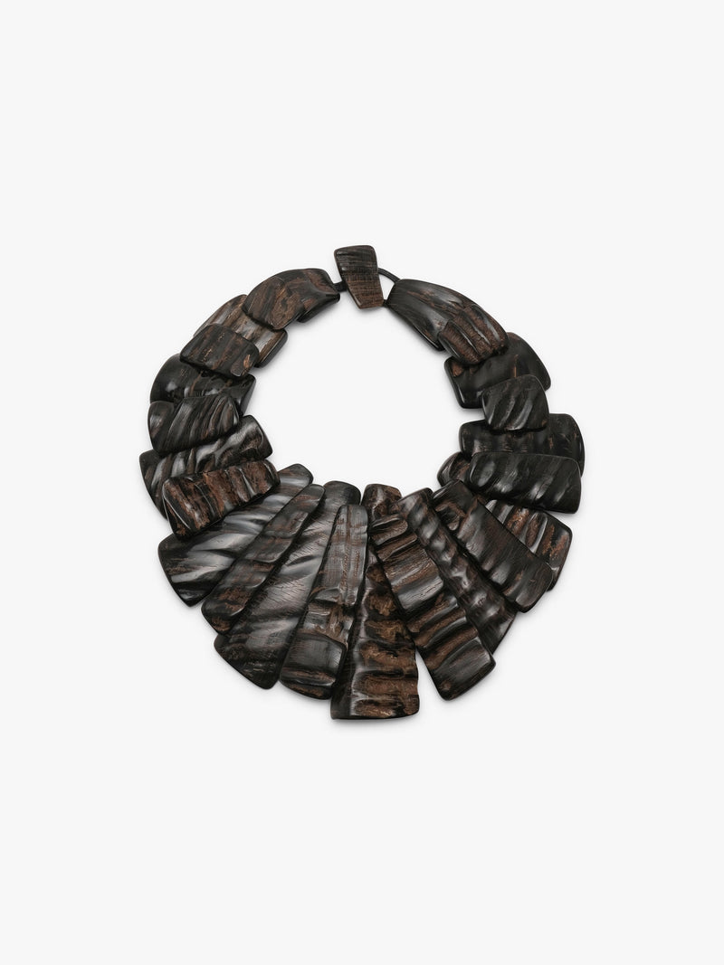 A dark brown horn statement necklace with layered, fan-shaped pieces and a small rectangular clasp, shown on a plain light gray background.