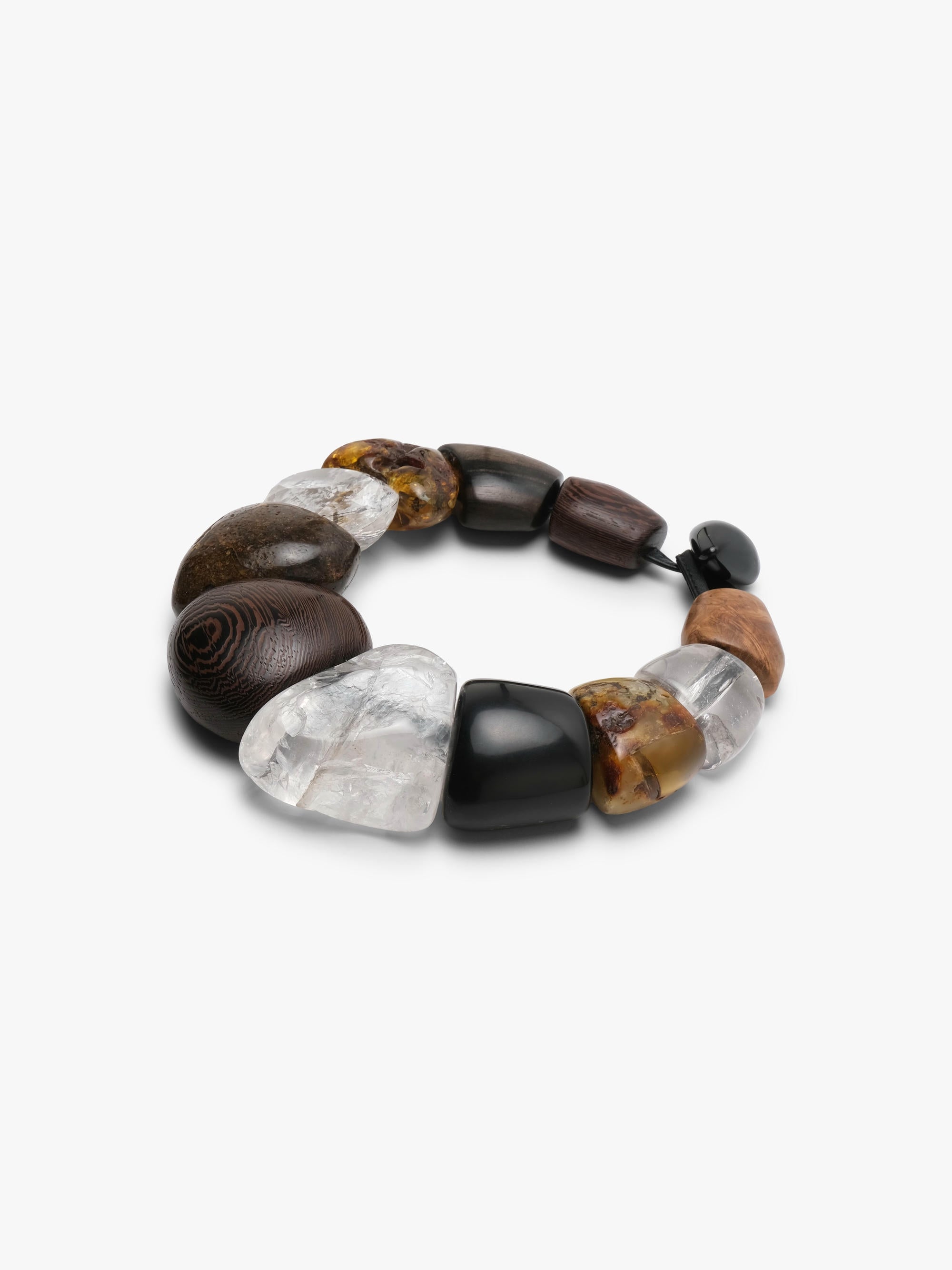 A beaded necklace featuring a mix of polished dark brown stones, clear quartz, black beads, and textured brown stones, arranged in a circle on a light gray background.