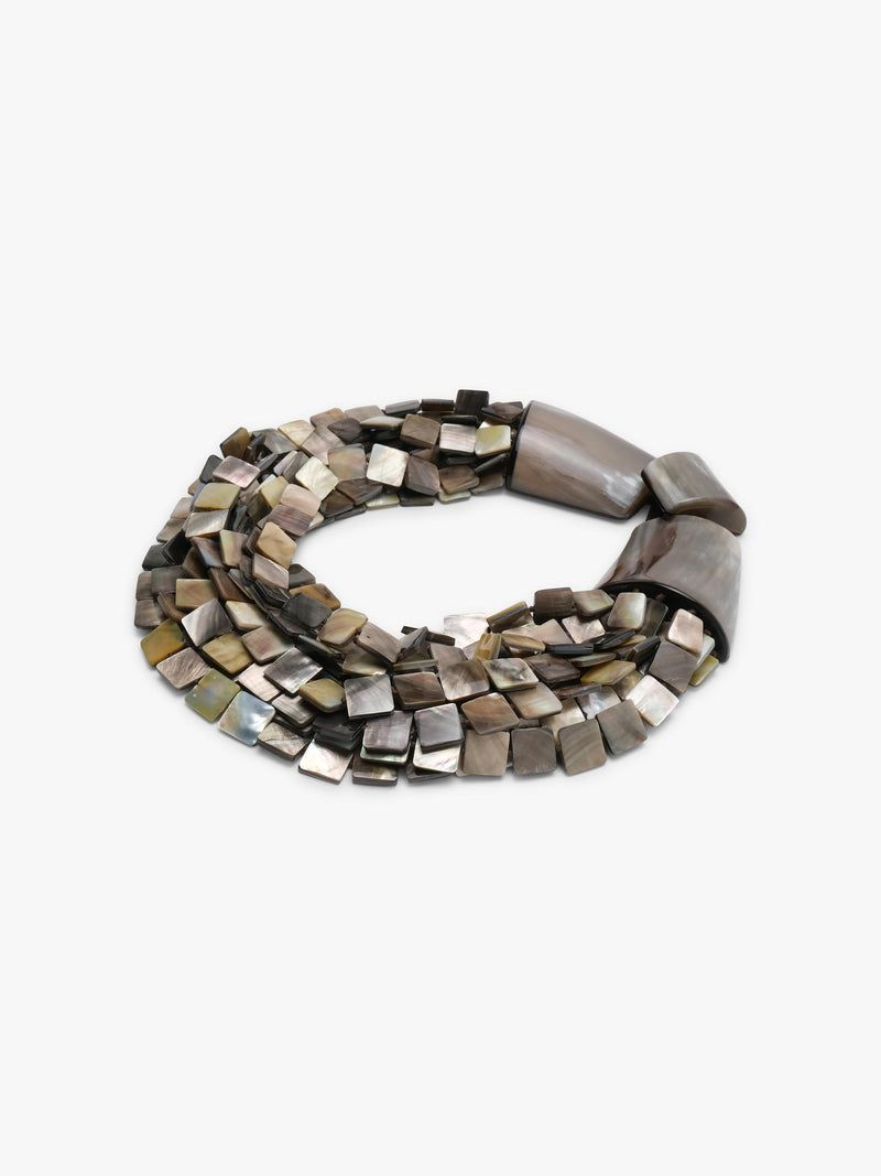 A multi-strand statement necklace featuring polished metallic square beads in silver, bronze, and gold tones, accented by two large dark brown shell-like end caps, shown on a plain light gray background.