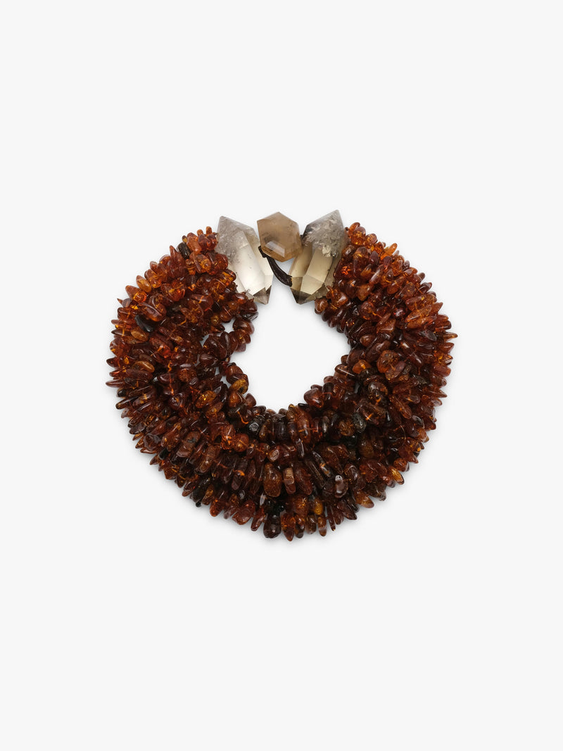 A chunky multi-strand amber necklace made of small, irregular brown amber pieces, accented with three raw citrine crystal beads in white, smoky gray, and light brown, set against a plain white background.