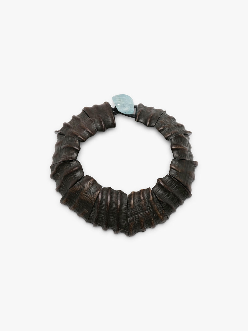 A dark brown textured leather necklace with a small light blue stone accent at the top, photographed on a clean white background.