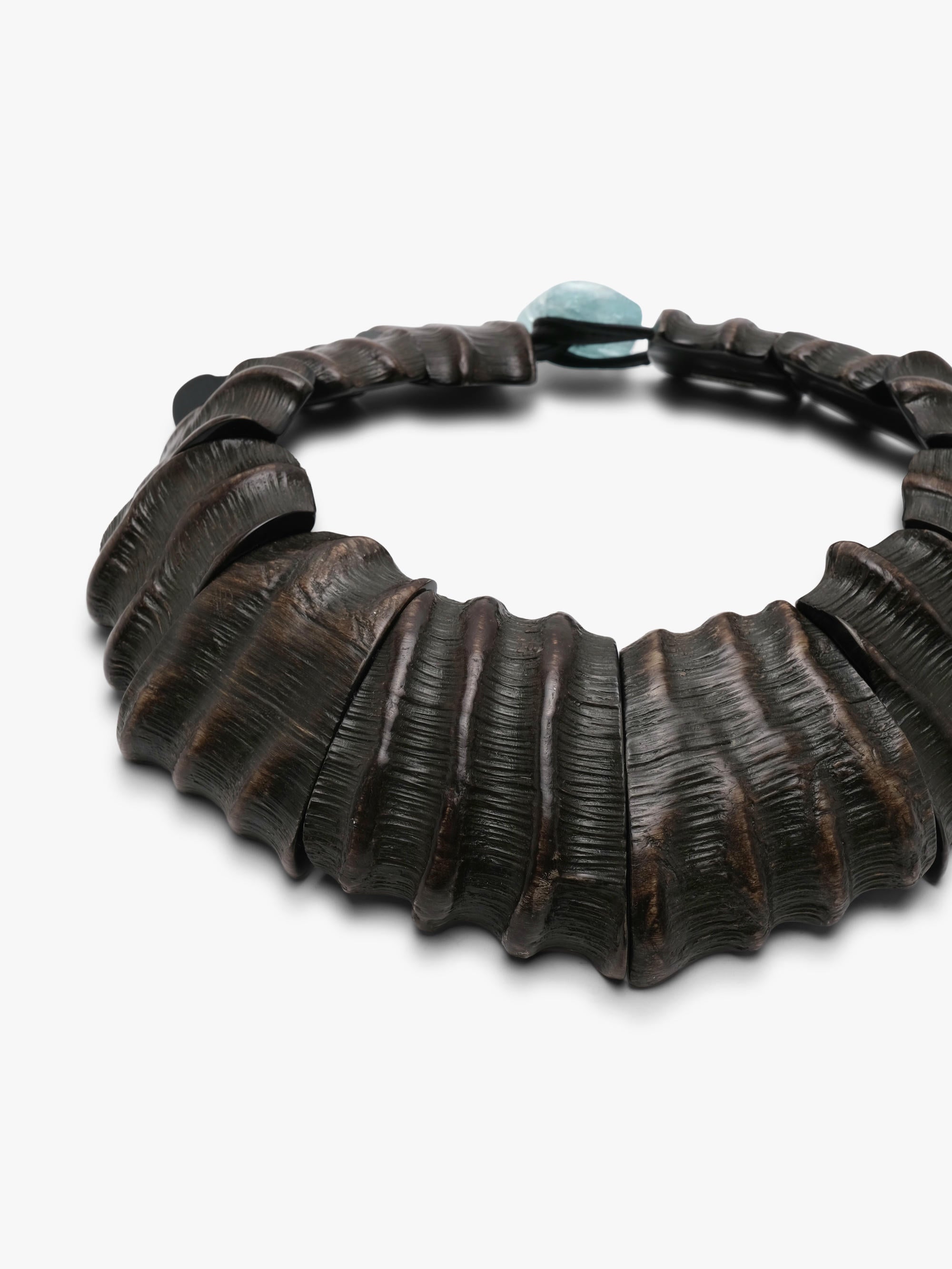 A dark brown textured leather necklace with a small light blue stone accent at the top, photographed on a clean white background.