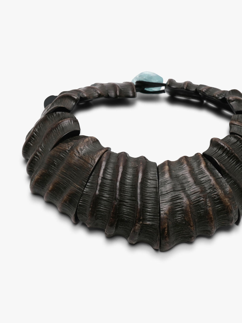 A dark brown textured leather necklace with a small light blue stone accent at the top, photographed on a clean white background.