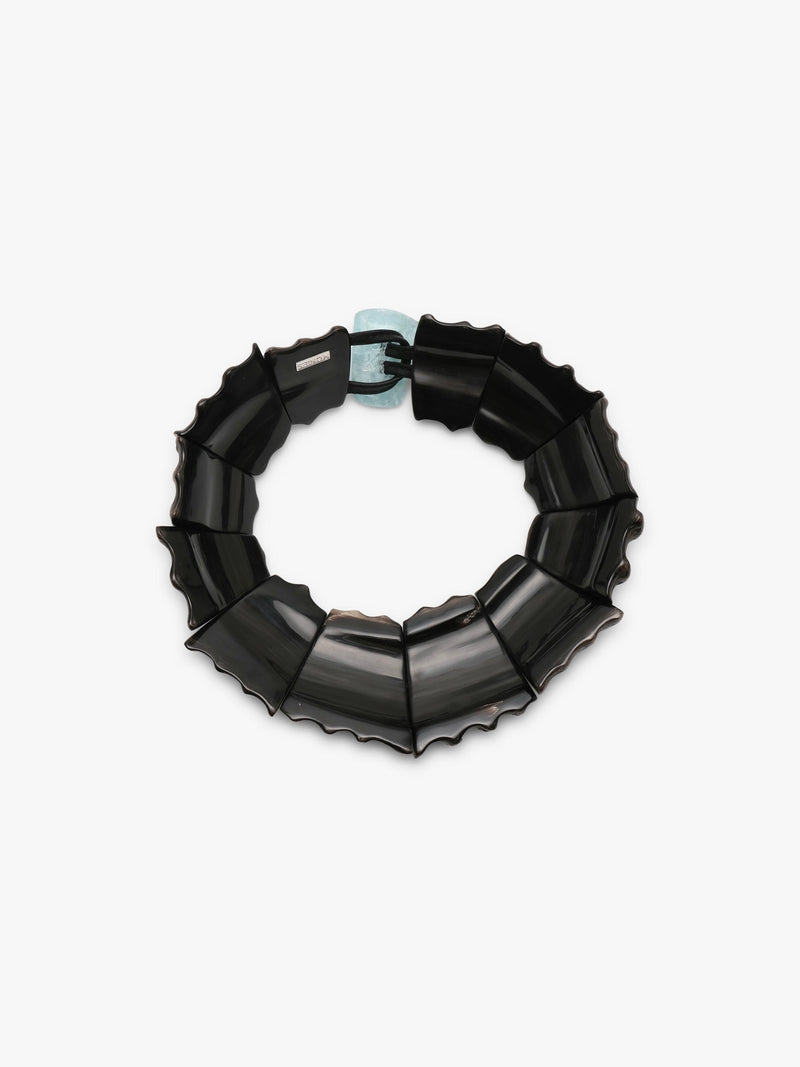 A black segmented chain-link necklace with a small light blue accent clasp, photographed on a clean white background.