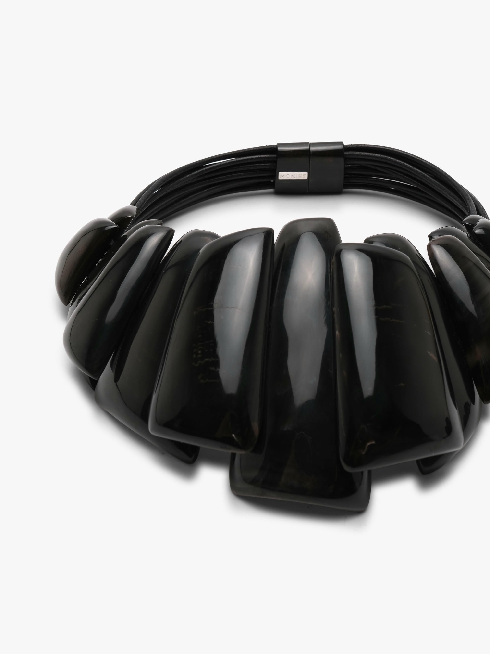 A chunky black beaded statement necklace with glossy, elongated teardrop-shaped beads and a black metal clasp, shown on a clean white background.