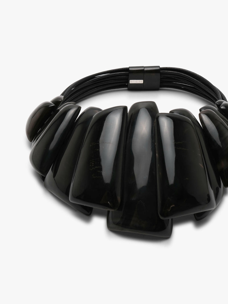 A chunky black beaded statement necklace with glossy, elongated teardrop-shaped beads and a black metal clasp, shown on a clean white background.