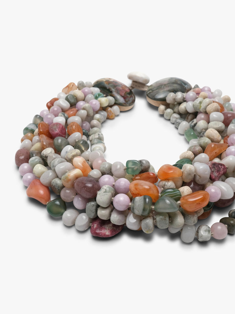 A multi-strand beaded necklace made of polished gemstone chips in various colors including pink, green, orange, gray, and white, arranged in a circular shape on a plain white background.