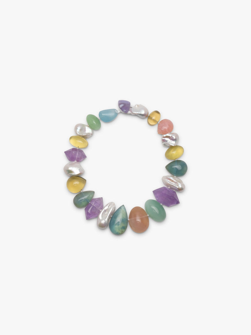 A single strand colorful necklace with green, blue, yellow beads and baroque pearls. Arranged on a white background. 