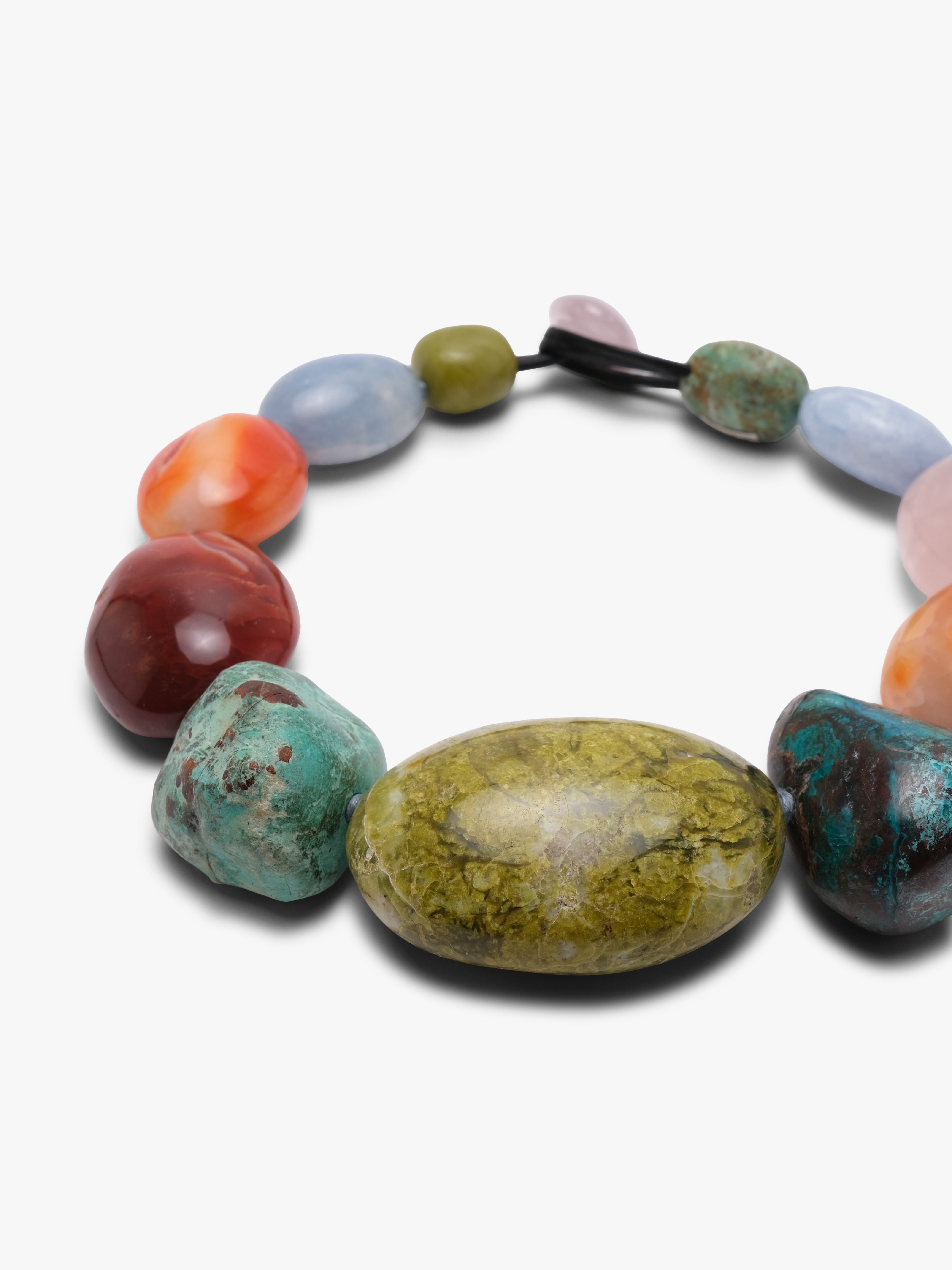 A multicolor stone bead necklace featuring a large central olive-green stone, surrounded by smaller stones in turquoise, coral, red, pink, and light blue, arranged on a light gray background.