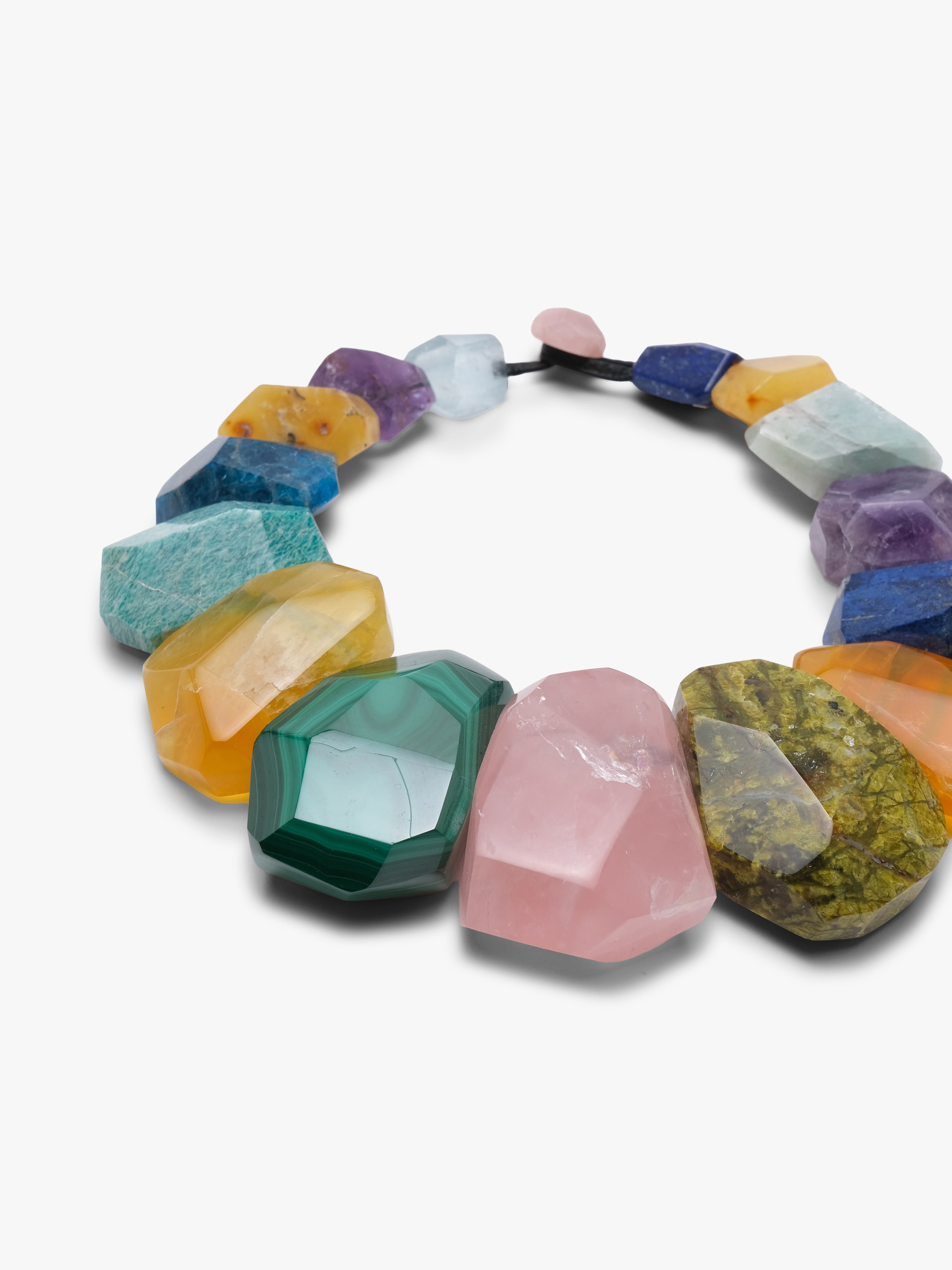 Colourful necklace is displayed o a white backgorund. Natural stones in blue, green, orange and pink. 