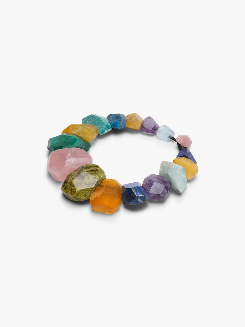 Colourful necklace is displayed o a white backgorund. Natural stones in blue, green, orange and pink. 