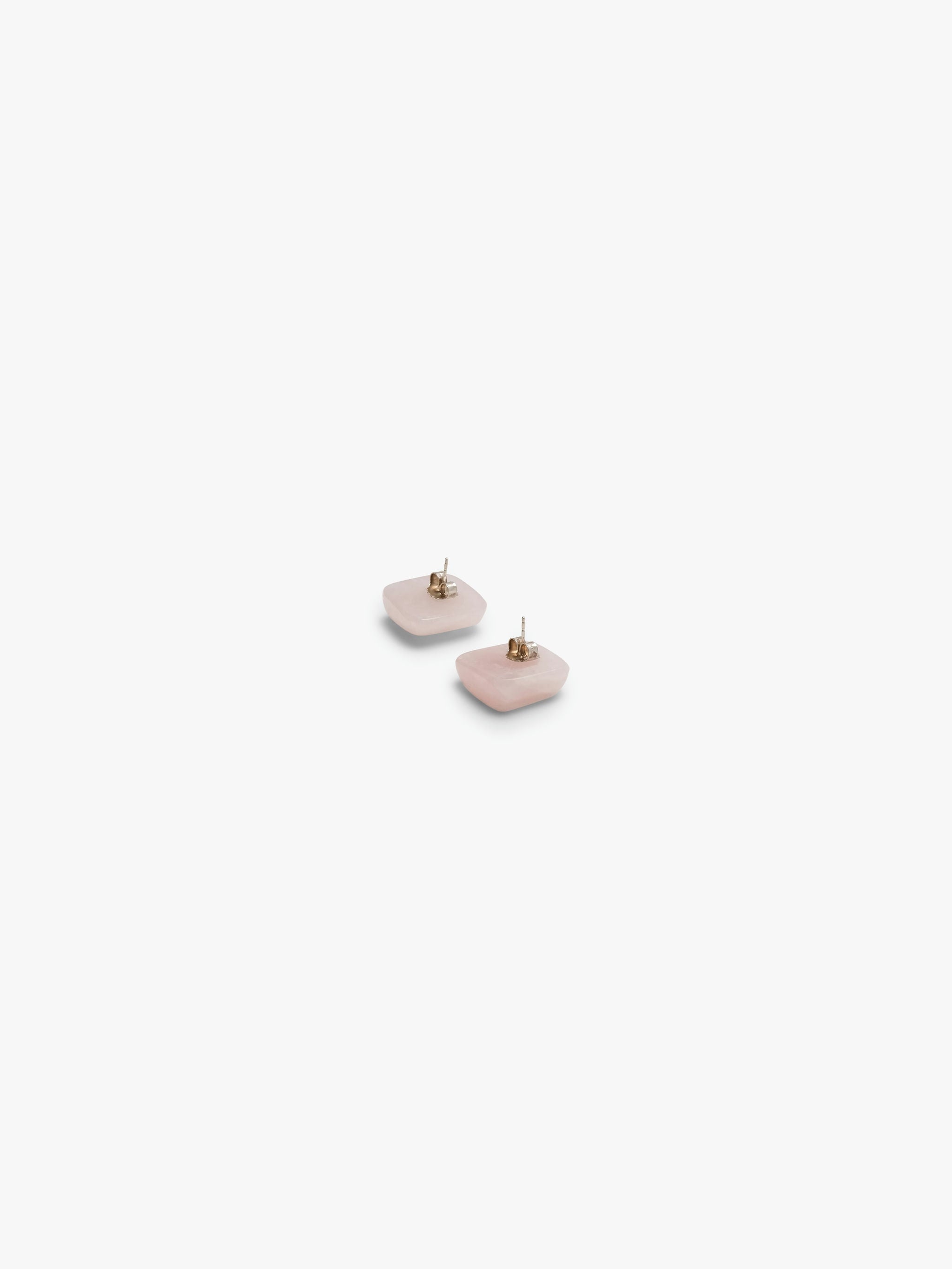 A pair of rose quartz stud earrings against a white background