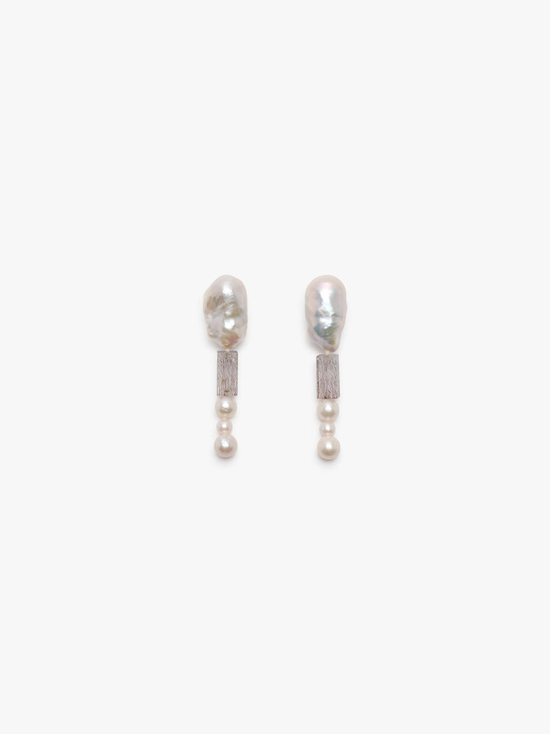 A pair of drop earrings featuring a baroque pearl, a textured rectangular quartz bead, and a small pearl bead at the bottom, set against a plain white background.