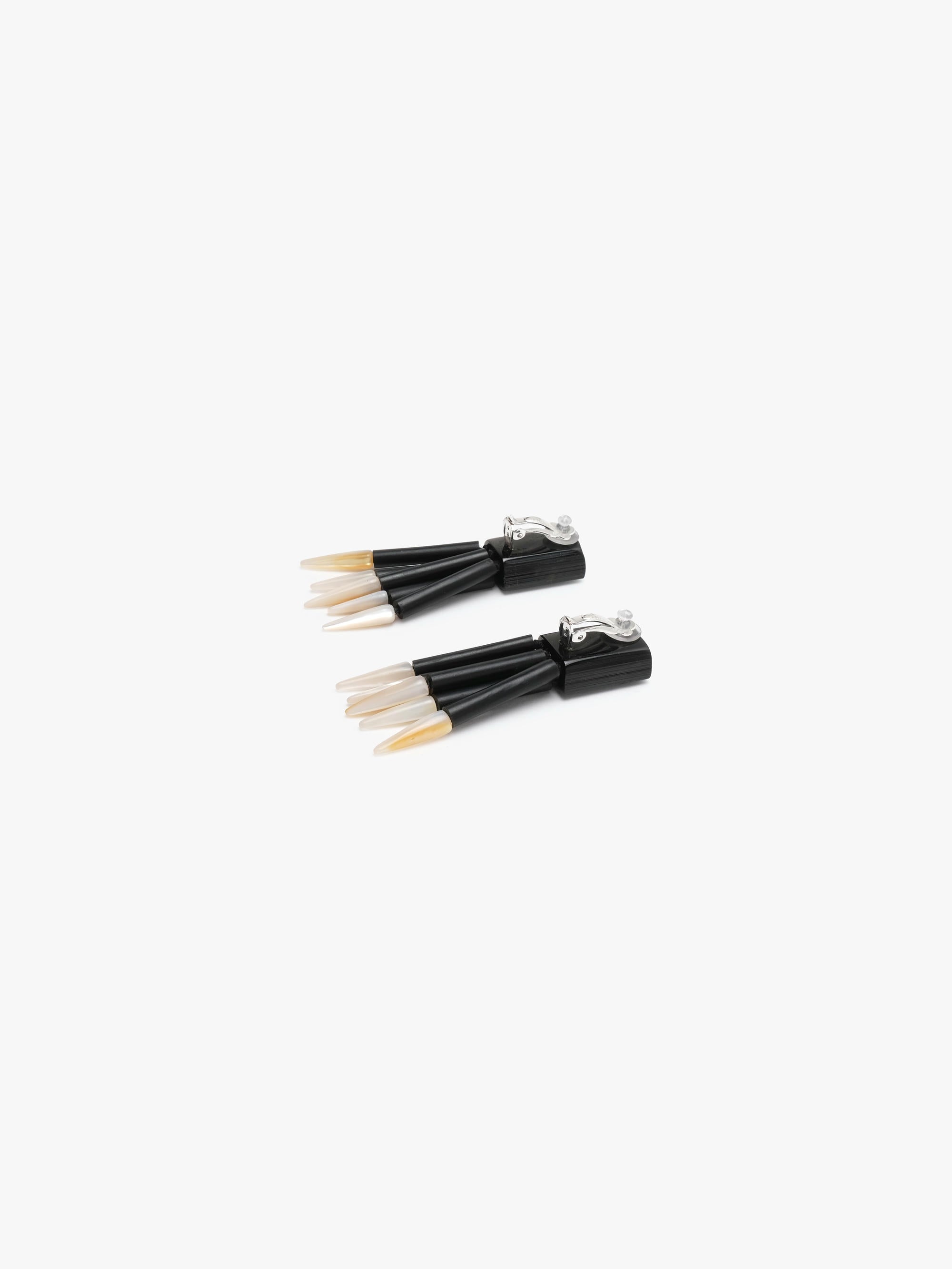 Black dangle earrings with white spears on a white background