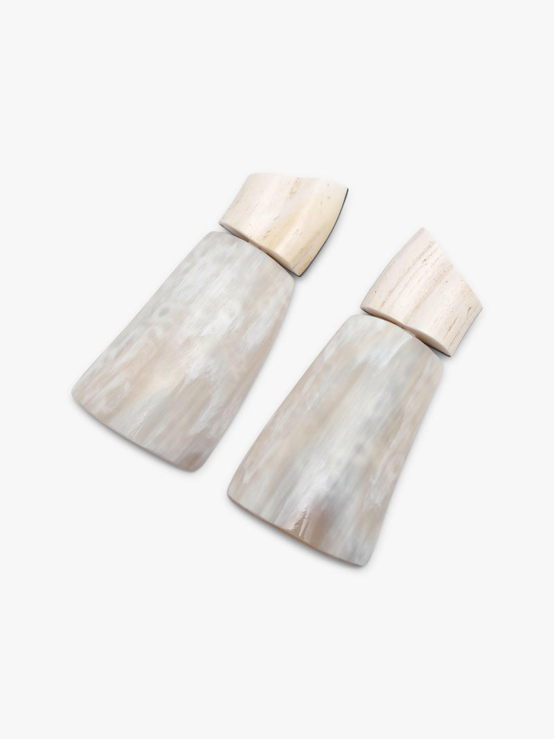 Pair of white earrings made of warthog tooth, cow horn and ebony on white background. 