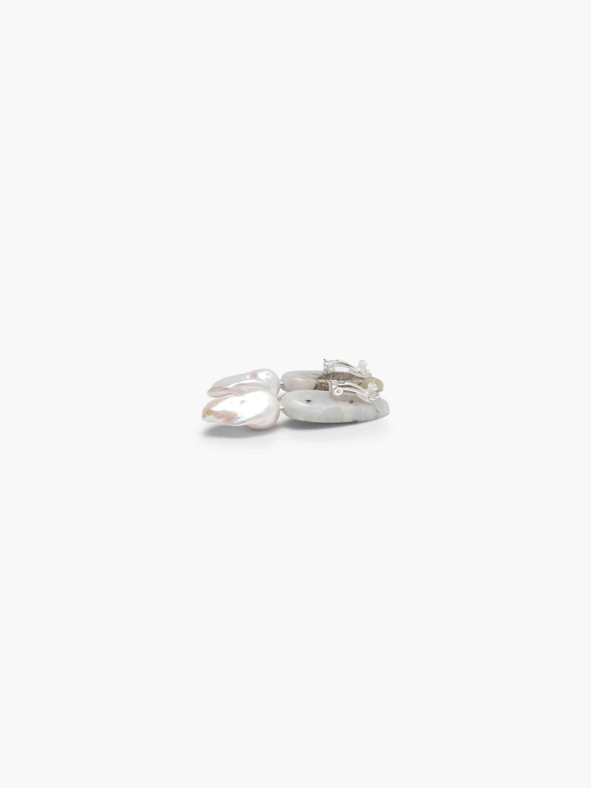 A pair of small drop earrings with green stone tops and baroque pearls, shown on a plain light gray background.