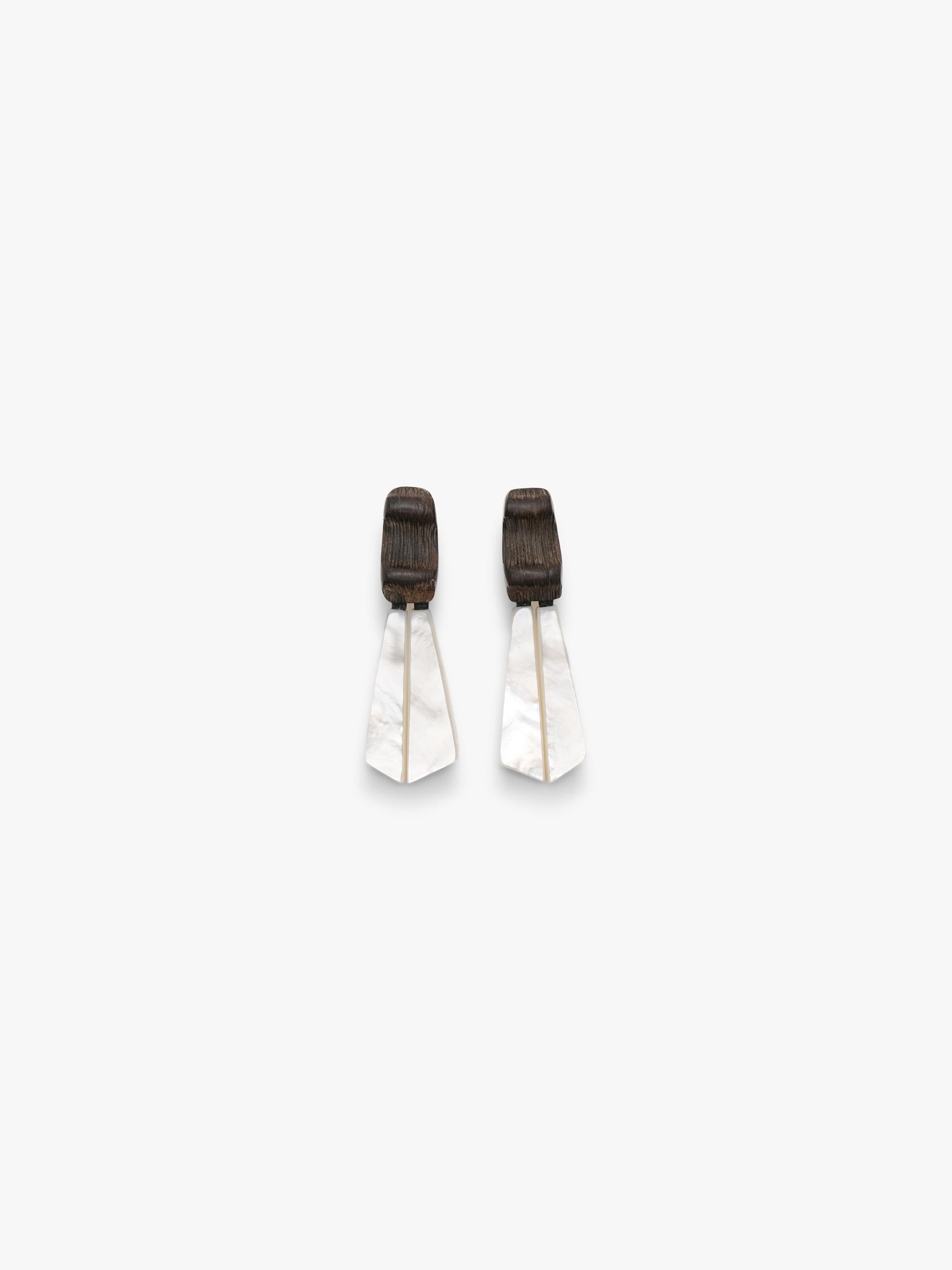 Pair of white earrings with black accents on a light gray background