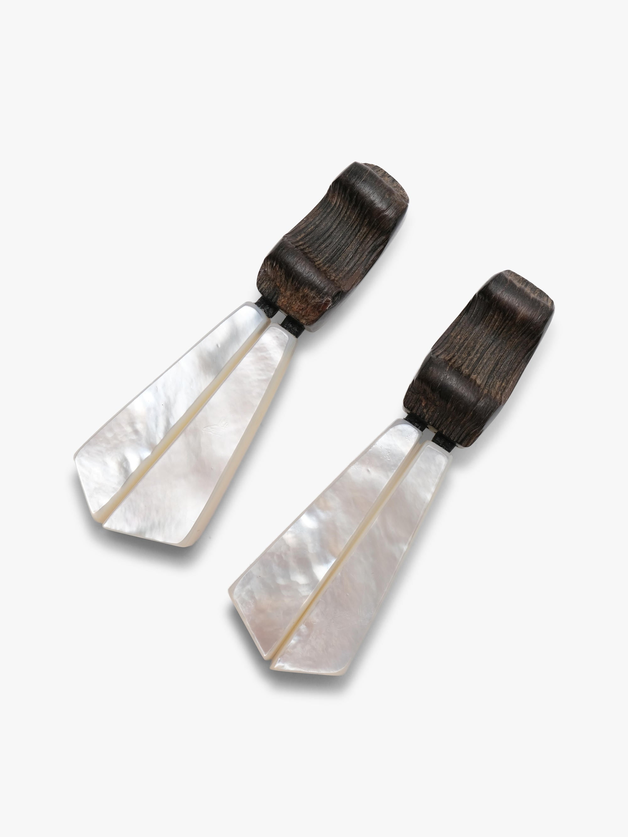 Pair of white earrings with black accents on a light gray background