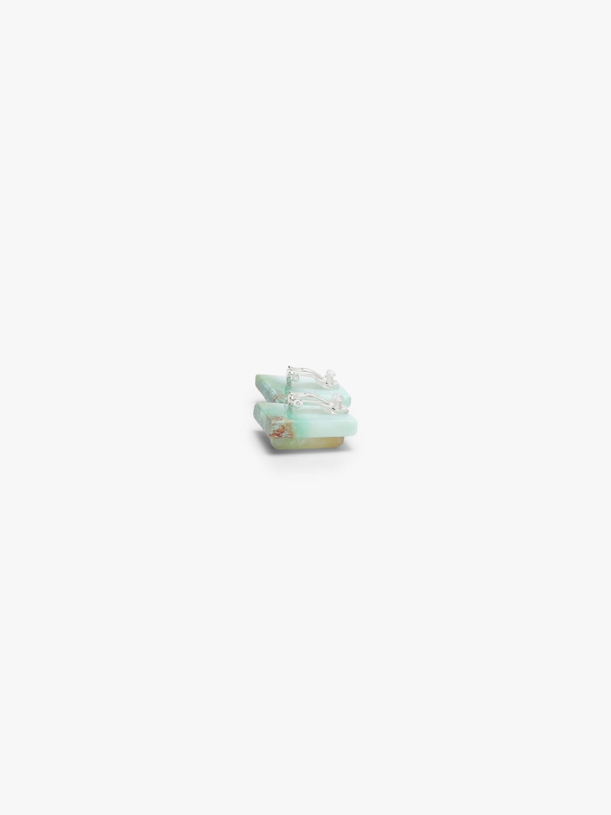 Pair of square-shaped earrings with blue stones on a white background