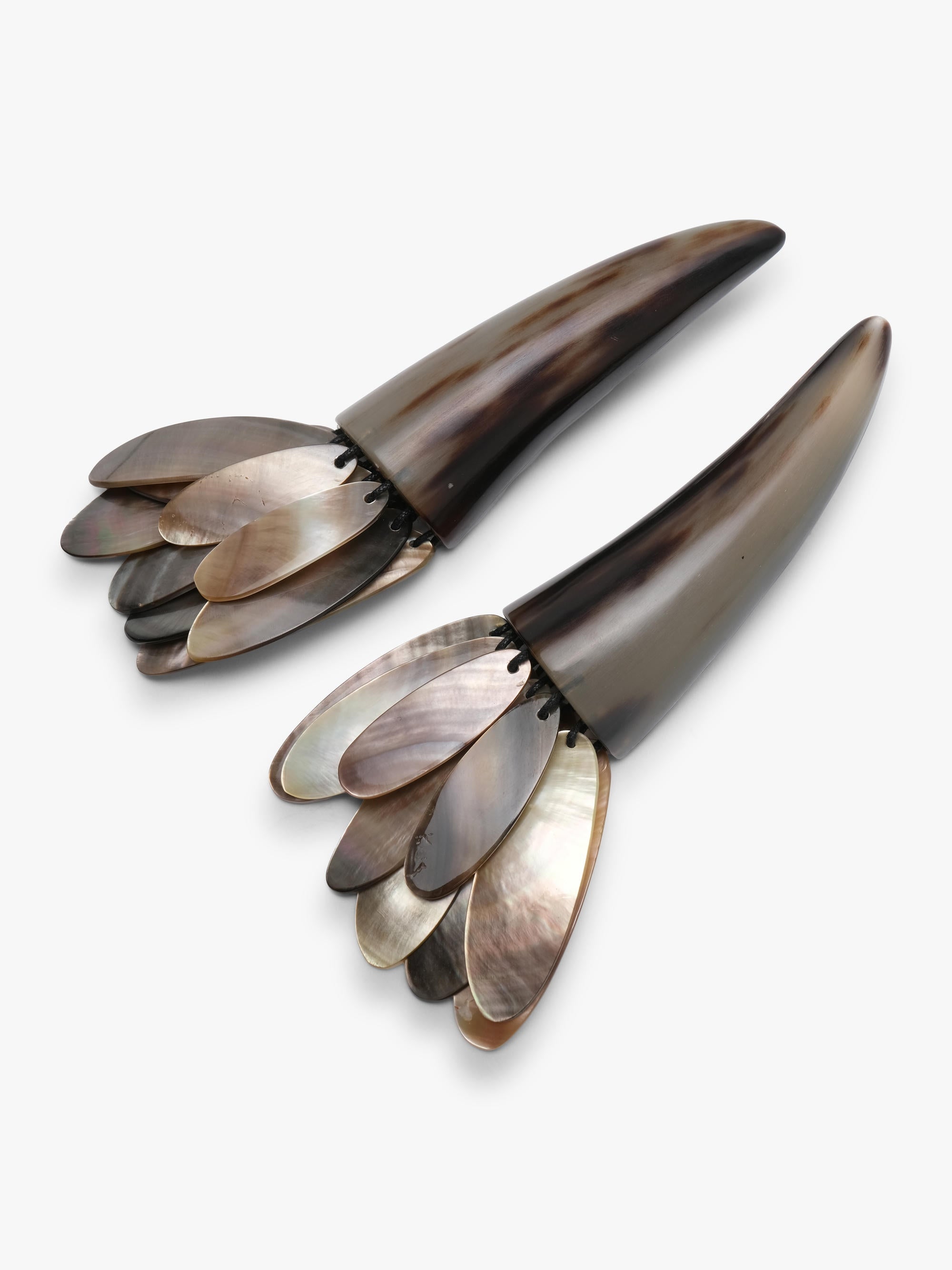 A pair of statement earrings featuring dark brown horn-like spikes with layered silver and iridescent shell petal details at the bottom, set against a plain light gray background.