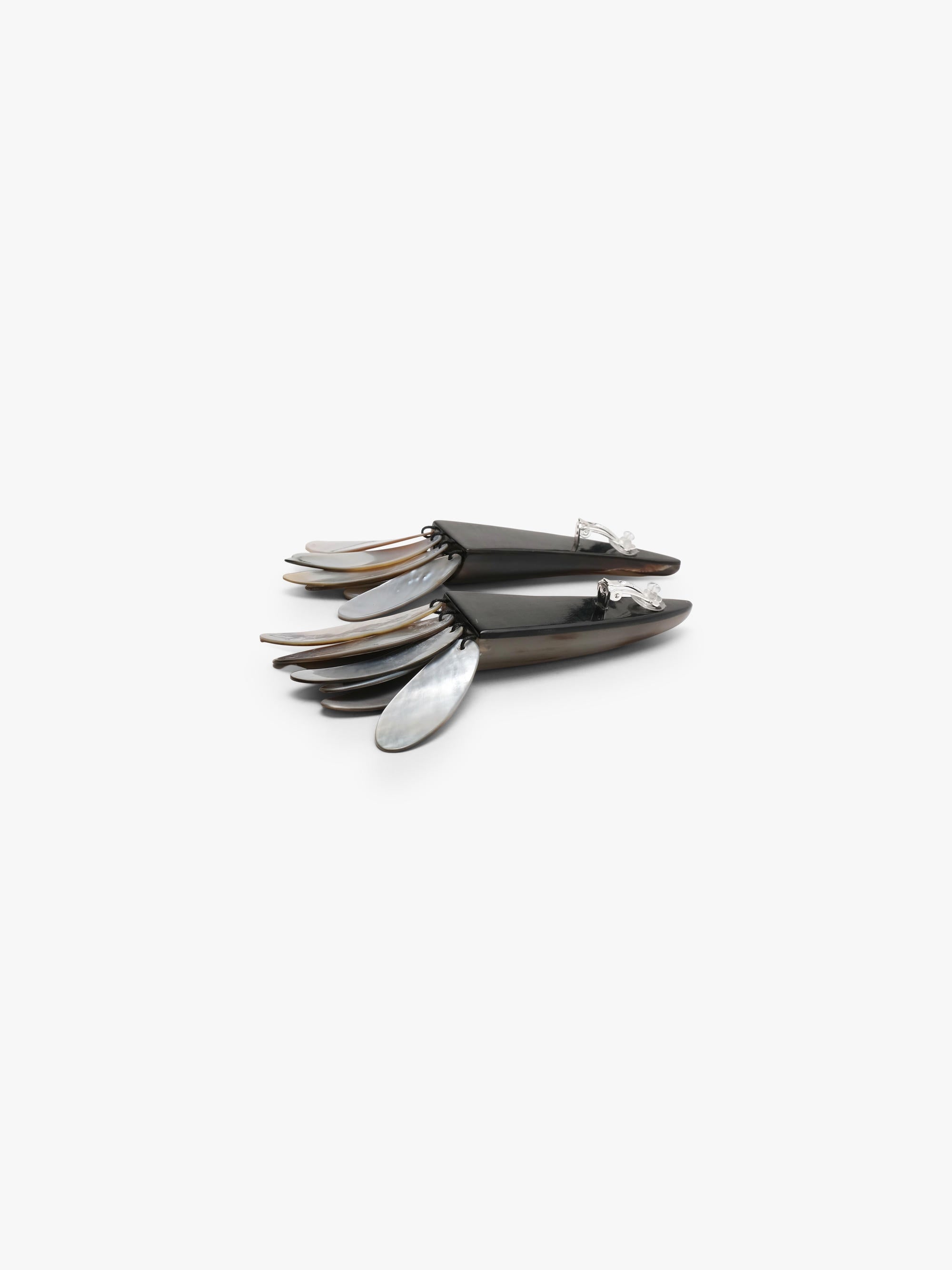 A pair of statement earrings featuring dark brown horn-like spikes with layered silver and iridescent shell petal details at the bottom, set against a plain light gray background.