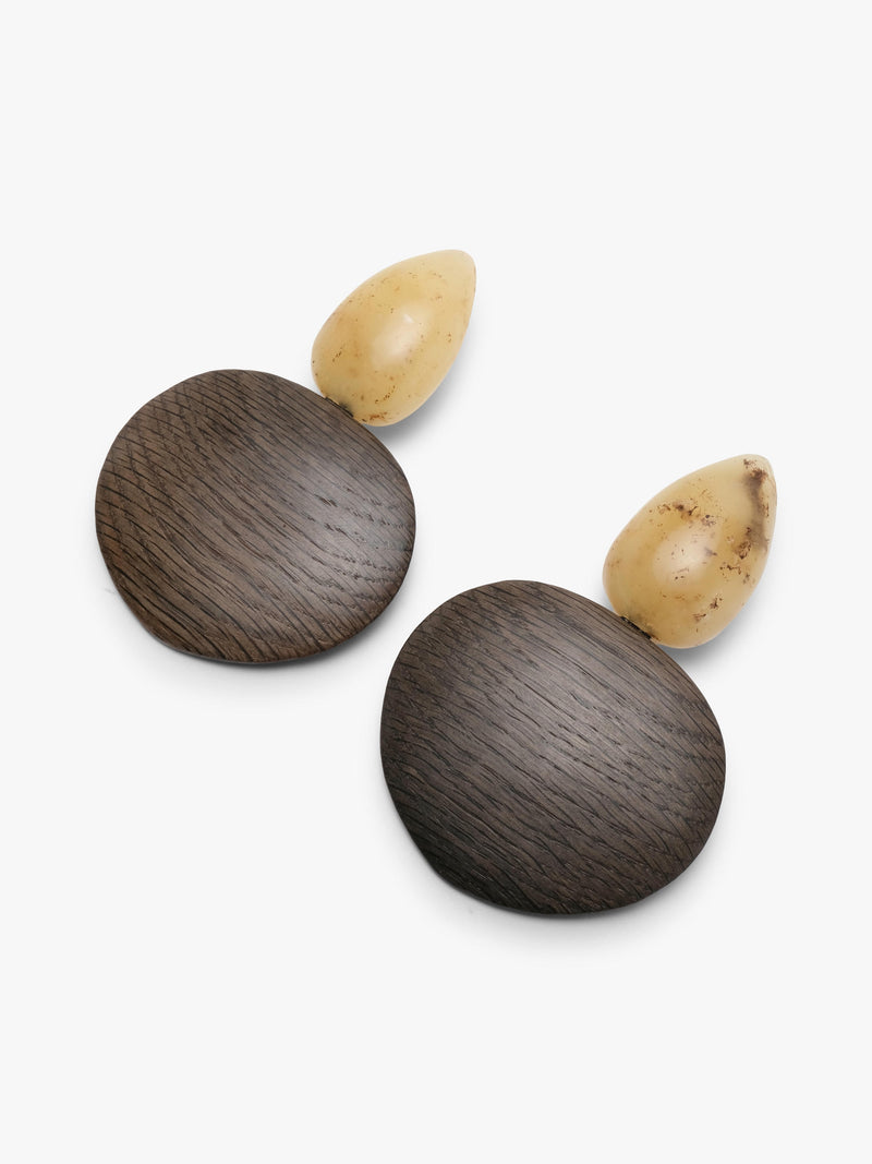 A pair of handmade wooden earrings featuring round dark brown wood discs and teardrop-shaped cream-colored amber tops, displayed on a clean white background.