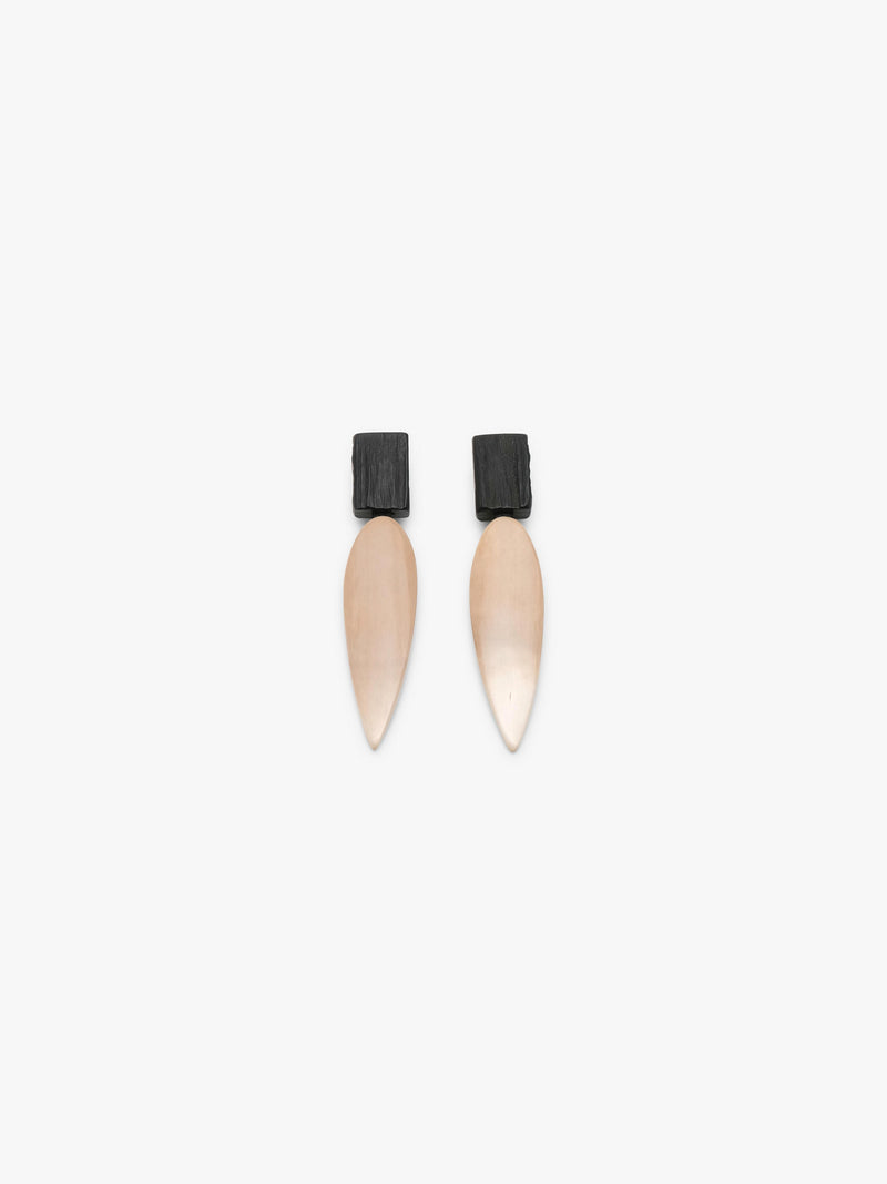 A pair of minimalist drop earrings featuring a matte black rectangular top and a teardrop-shaped pendant in a warm champagne beige finish, set against a solid off-white background.