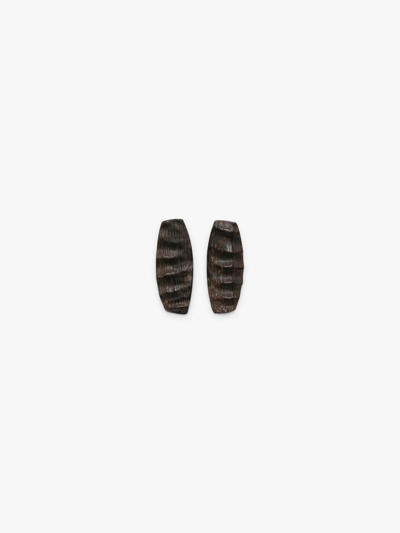 A pair of elongated, textured horn earrings in dark brown, displayed on a white background