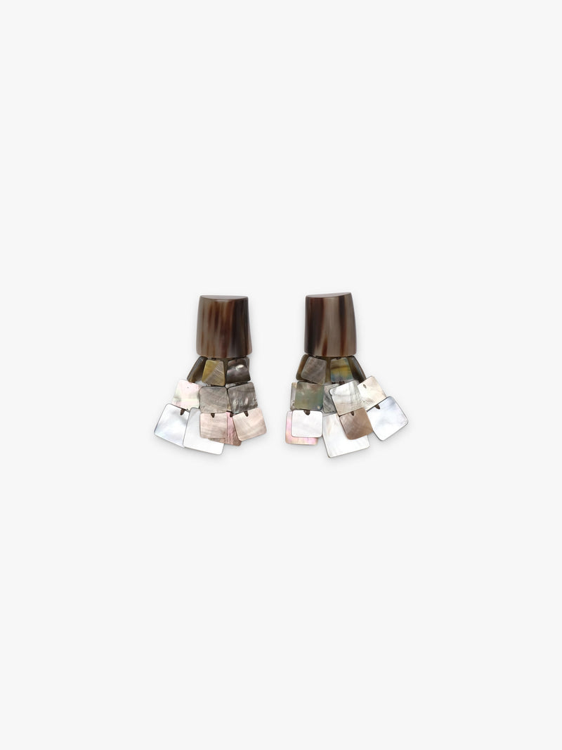 A pair of statement earrings made from stacked iridescent mother-of-pearl square tiles and dark brown striped cylindrical tops, displayed on a light gray background.