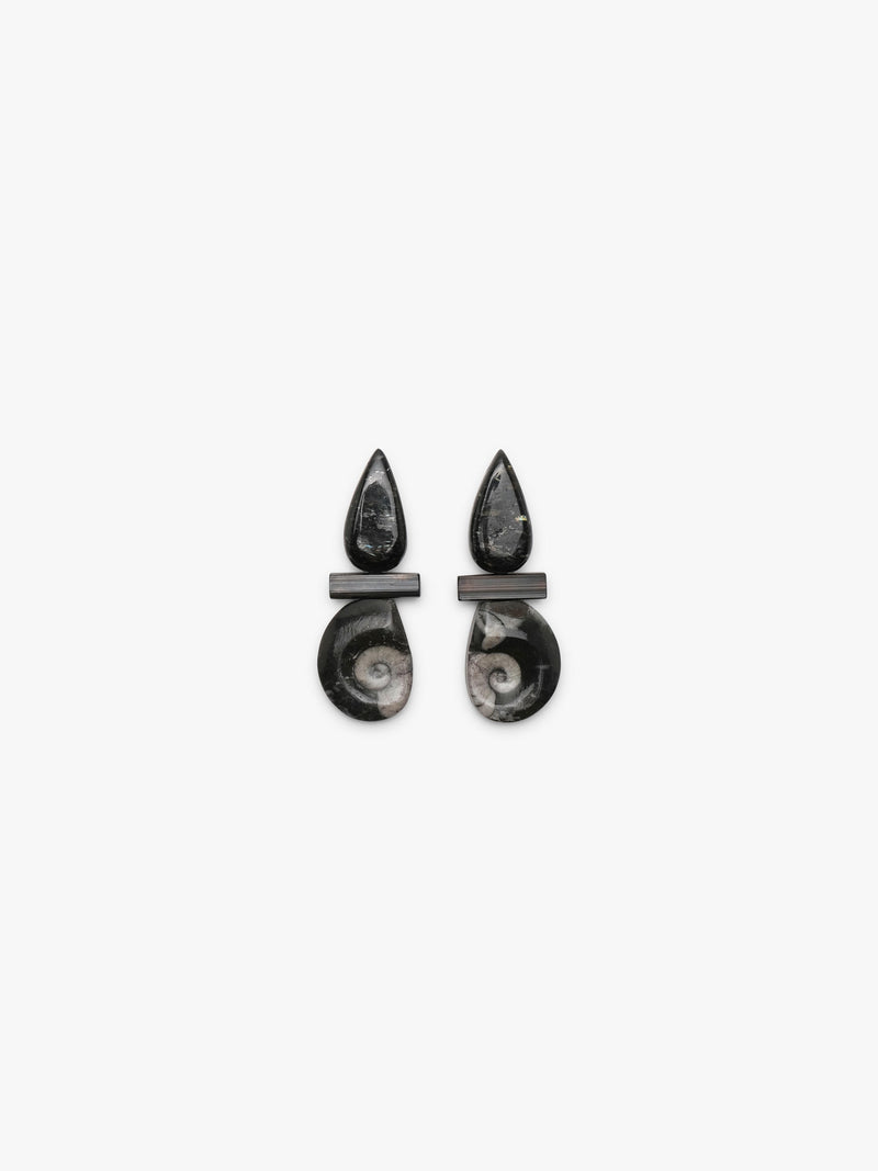 A pair of black teardrop-shaped earrings with a central rectangular bar and a lower drop featuring a polished spiral ammonite shell inlay, shown on a light gray background.