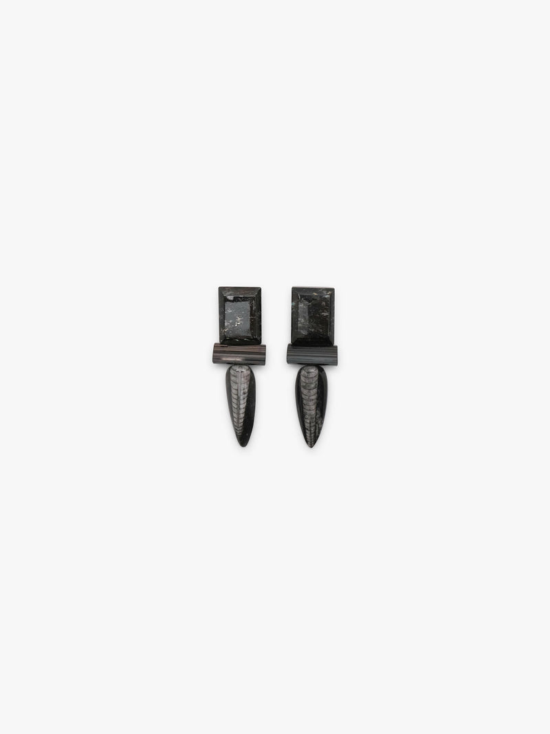 A pair of dark metallic drop earrings with rectangular posts and elongated teardrop-shaped drops, shown against a plain light gray background.