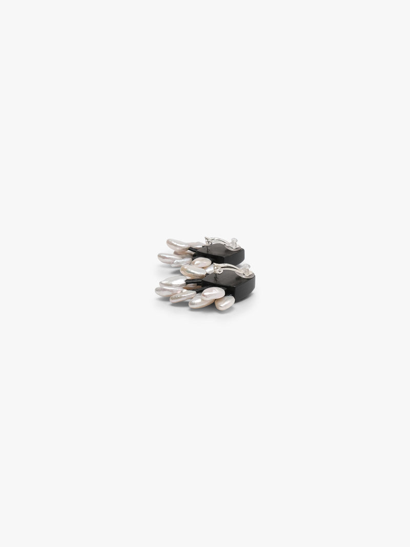 The backside of A pair of black fan-shaped stud earrings with dangling silver-toned and white freshwaterpearls, shown on a plain light gray background.