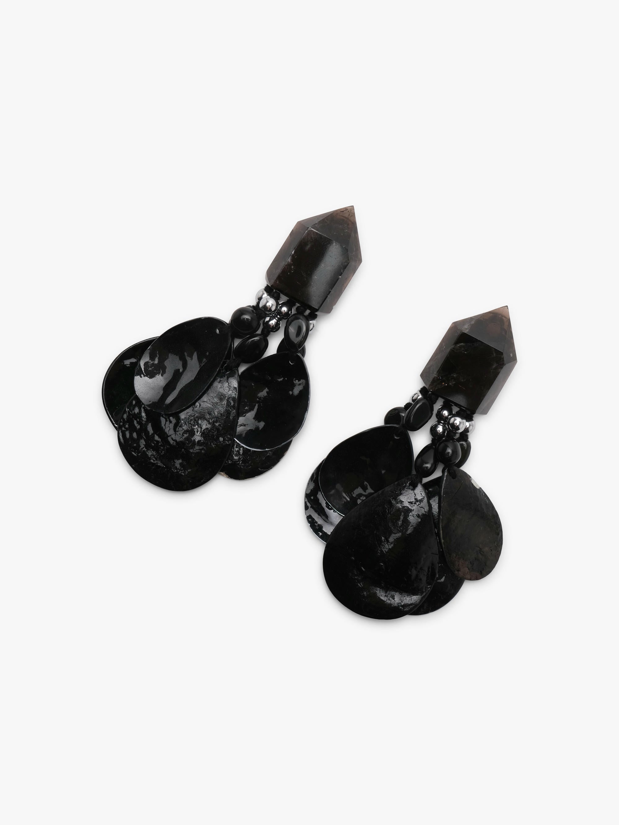 A pair of black dangle earrings with a geometrical top and black shell tassles, displayed on a white background
