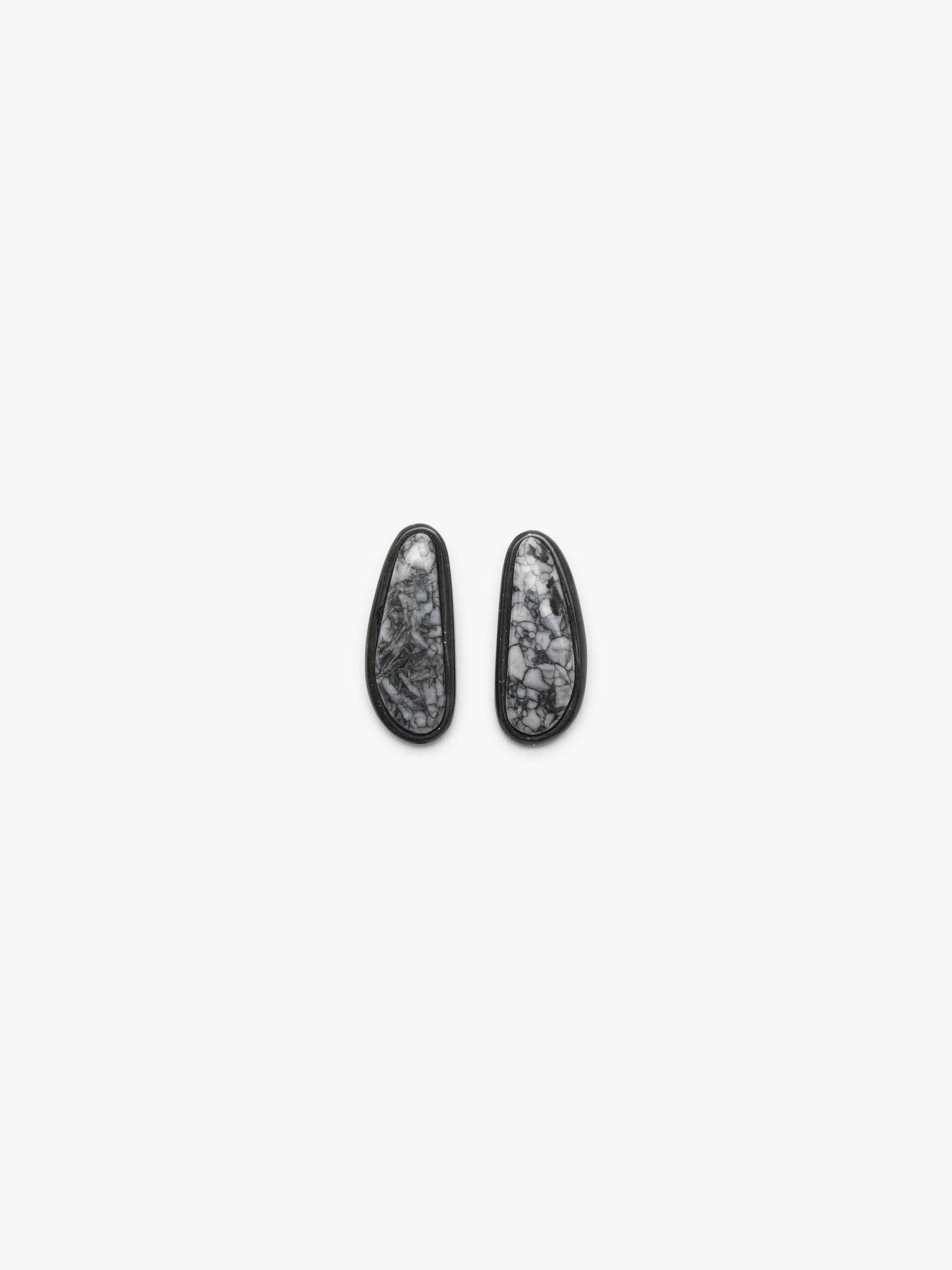 A pair of black-framed oval stud earrings with white and gray marbled stone inlays, displayed on a clean white background.