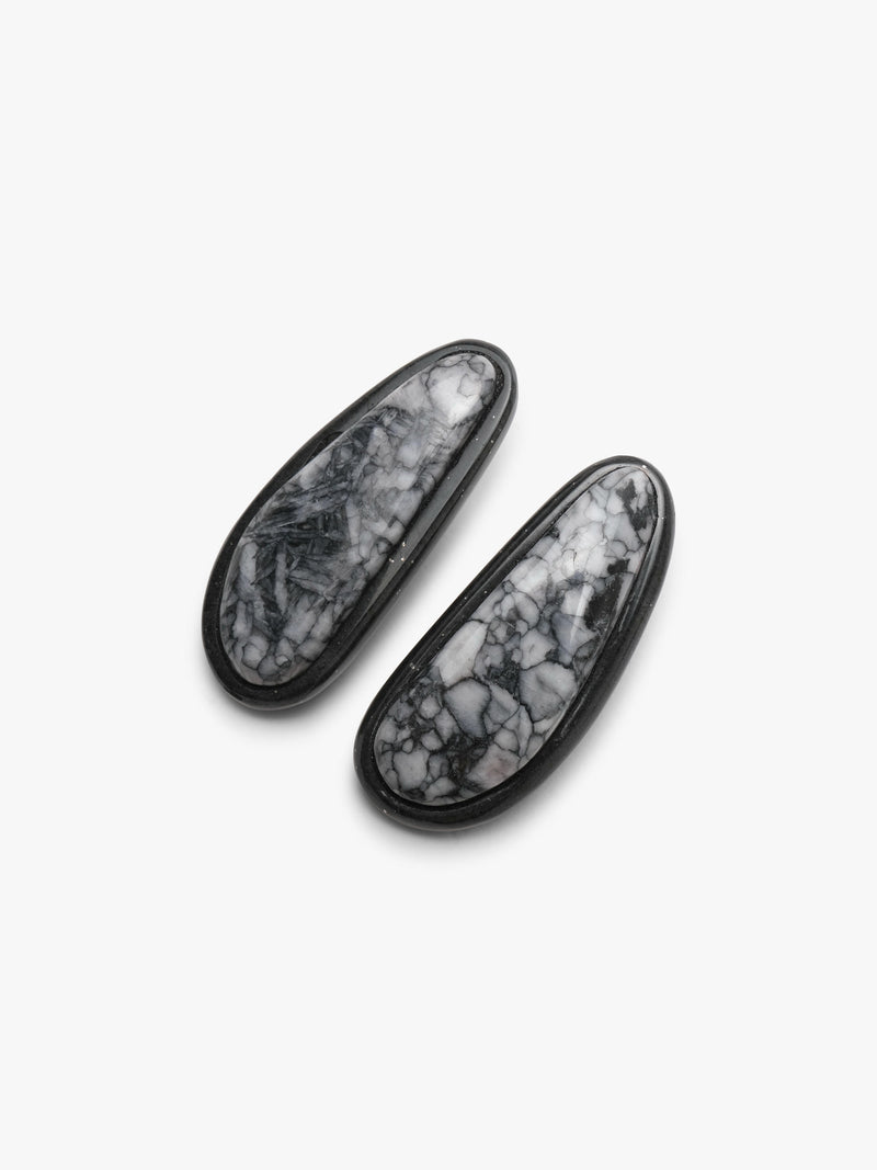 A pair of black-framed oval stud earrings with white and gray marbled stone inlays, displayed on a clean white background.