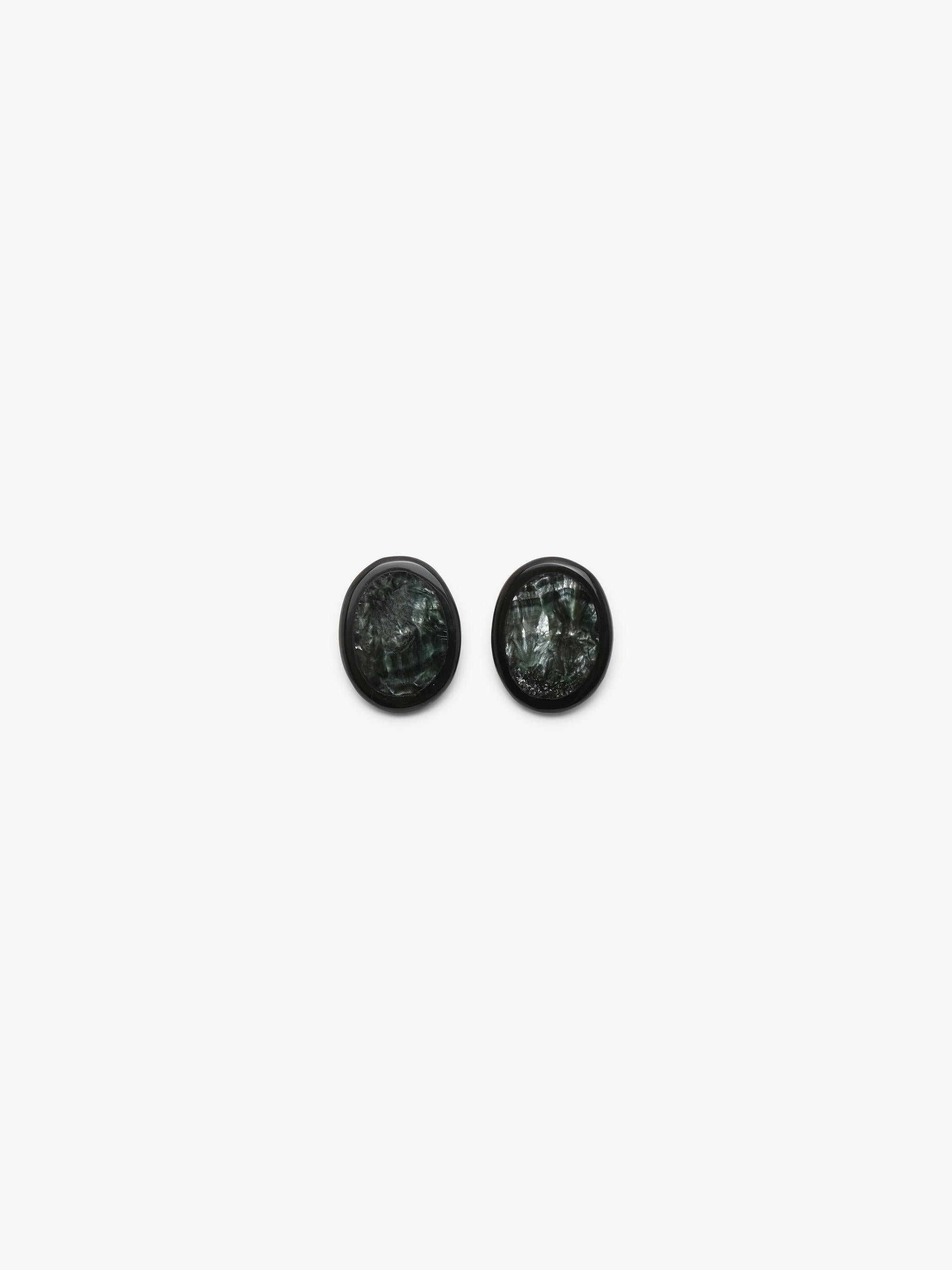 A pair of oval stud earrings with dark green, textured stone inlays set in black metal, shown on a plain light gray background.