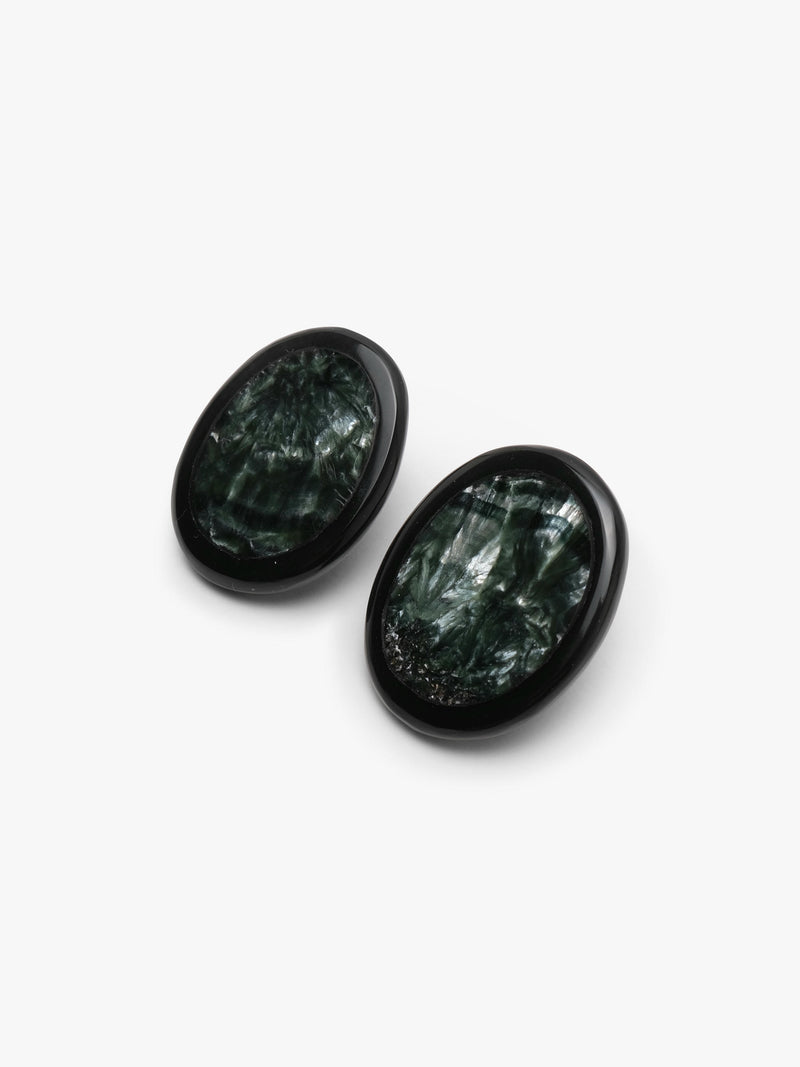 A pair of oval stud earrings with dark green, textured stone inlays set in black metal, shown on a plain light gray background.