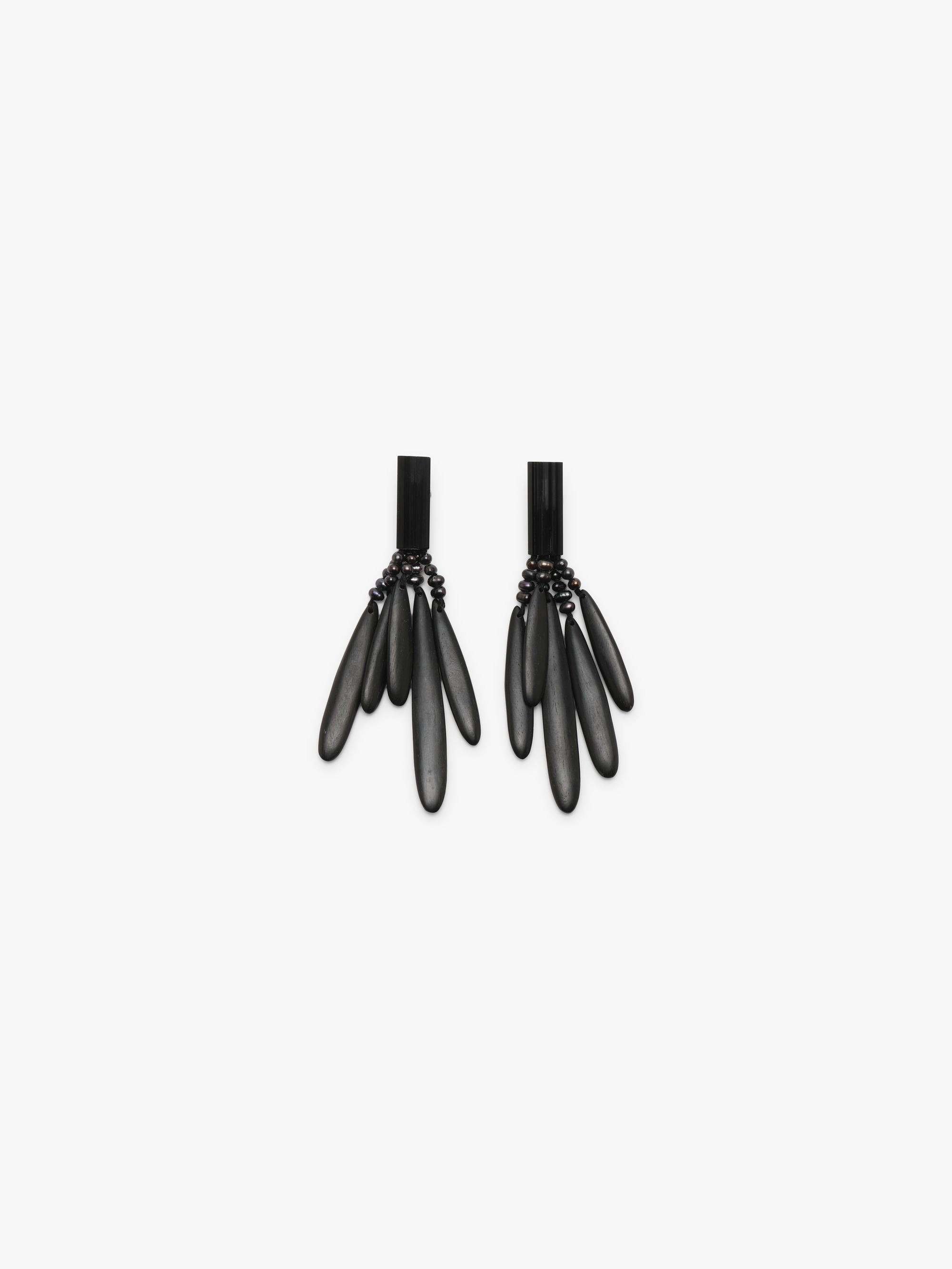 A pair of black statement dangle earrings with a textured top band and five elongated teardrop-shaped drops, shown against a plain light gray background.