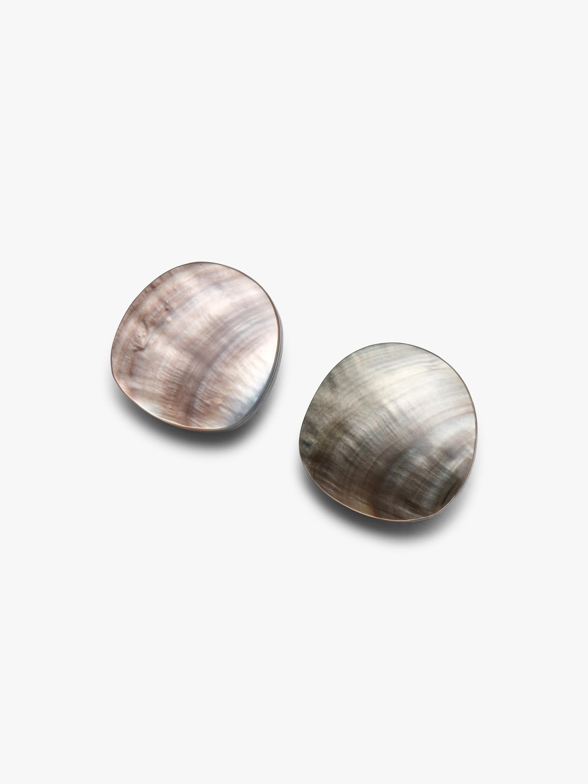 A pair of oval stud earrings with a natural mother-of-pearl shell finish, featuring iridescent brown, gray, and white swirls, set against a plain light gray background.