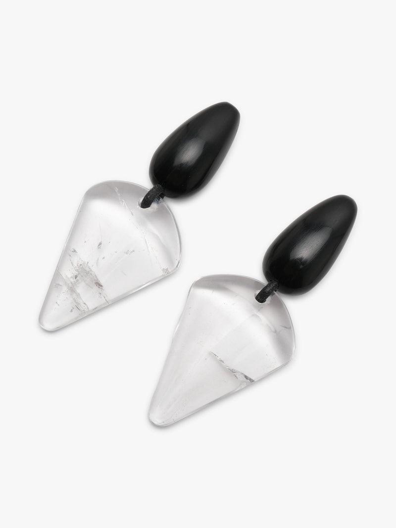 A pair of geometric drop earrings featuring clear, faceted triangular stone pendants with subtle white veining, suspended from smooth, glossy black teardrop-shaped studs, shown on a light gray background.