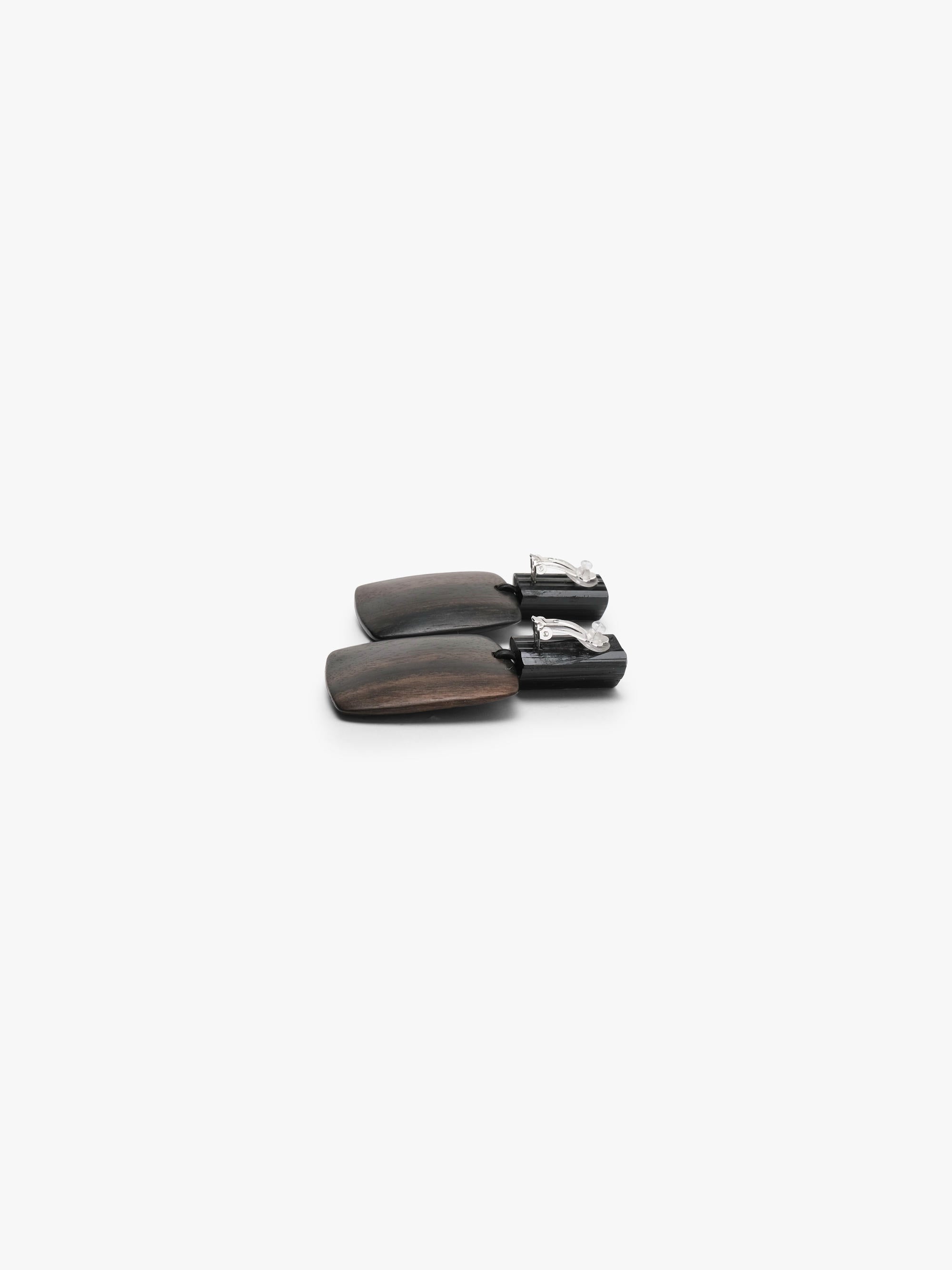 A pair of dark brown wooden drop earrings with a matte finish and cylindrical posts, displayed on a clean white background.