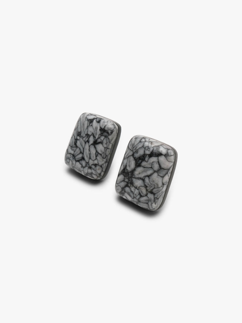 A pair of button earrings with a black and grey marble pattern, displayed on a white background